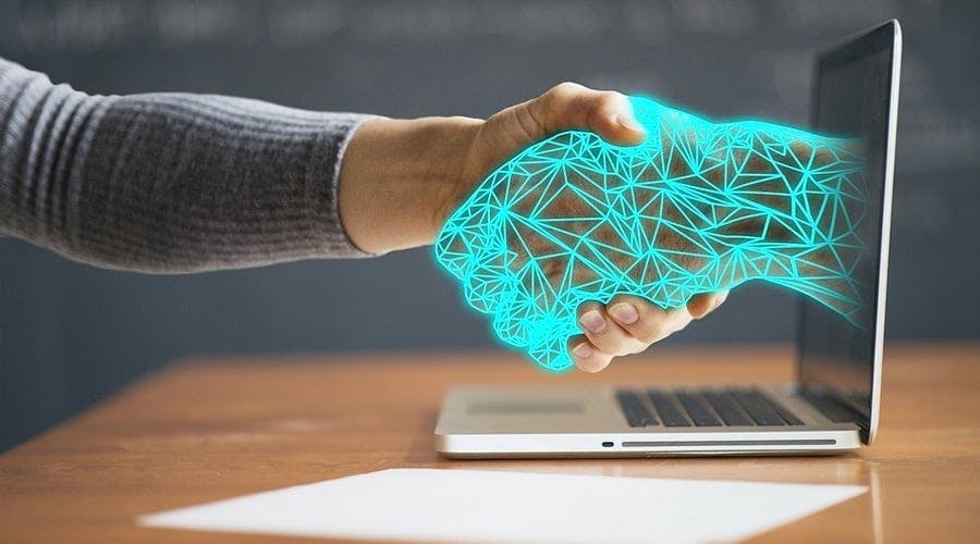 Mãos dadas com uma inteligência artificial saindo da tela de um computador cinza