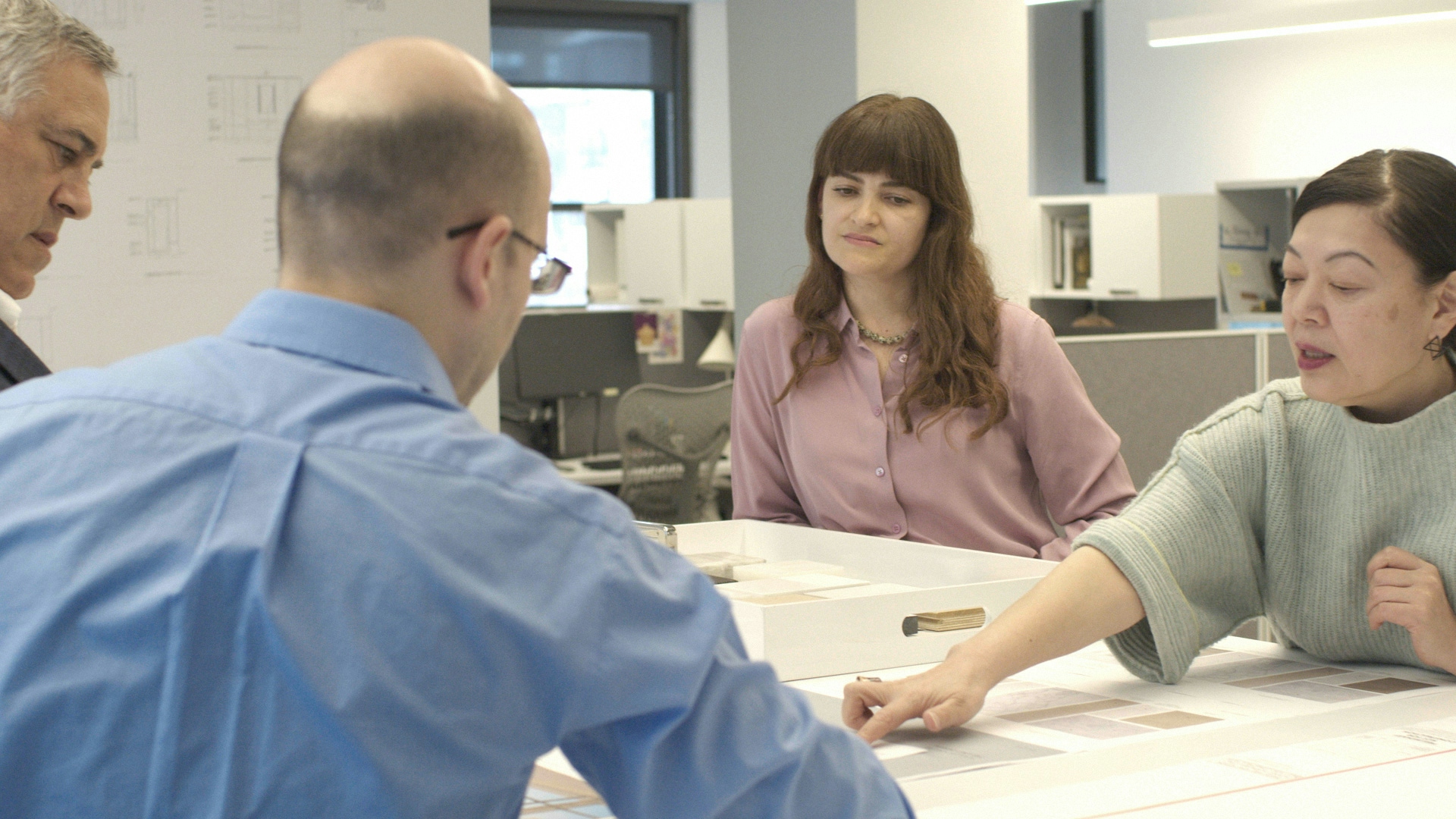 Two women and two men sitting at a table and pointing at architecture models for Pembrooke & Ives.