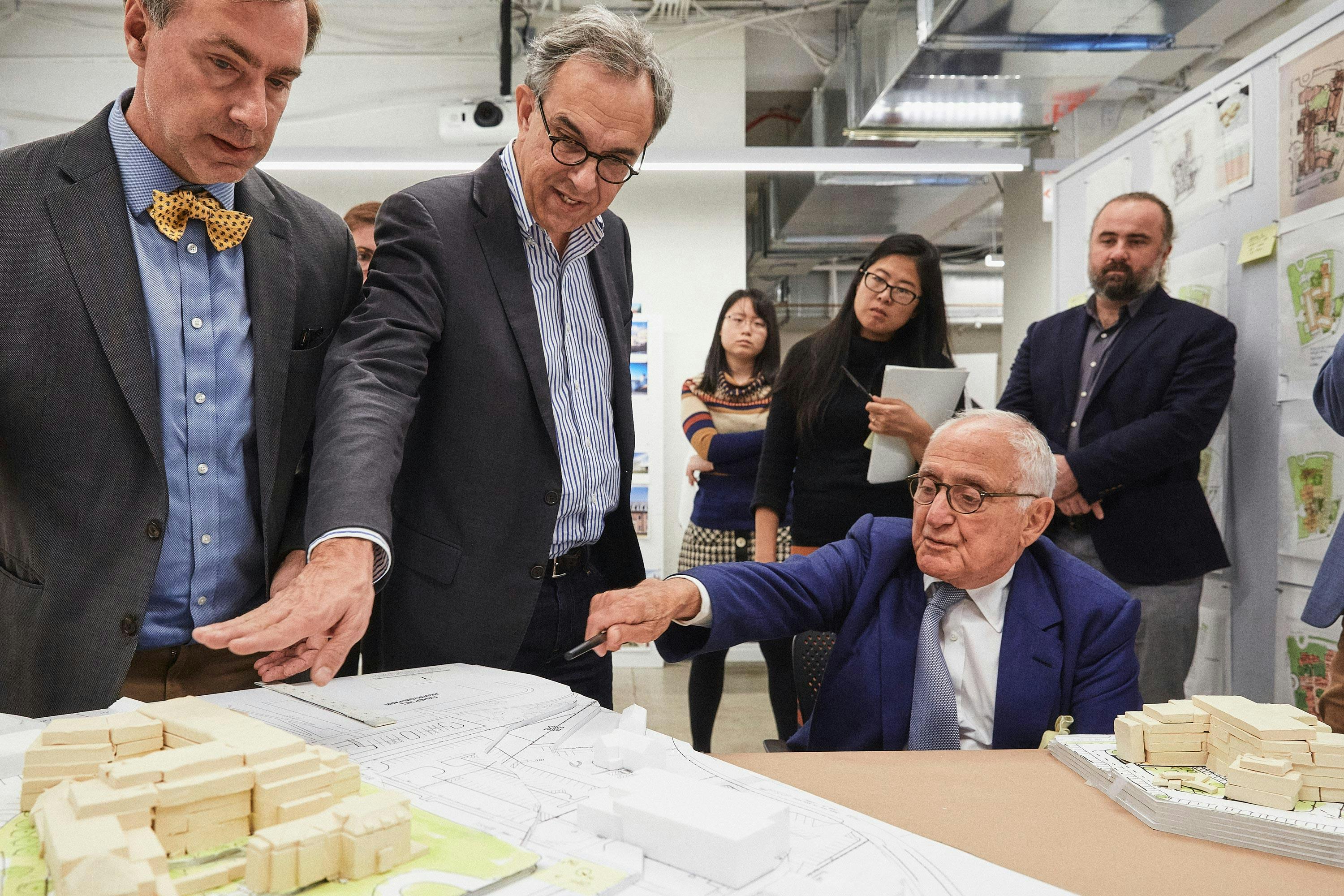 Robert A.M. Stern Architects team surrounding a table and discussing the architecture of one of their 3D model designs.
