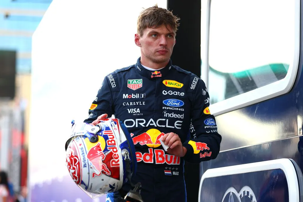 And F1 racer carries his helmet looking forward and serious