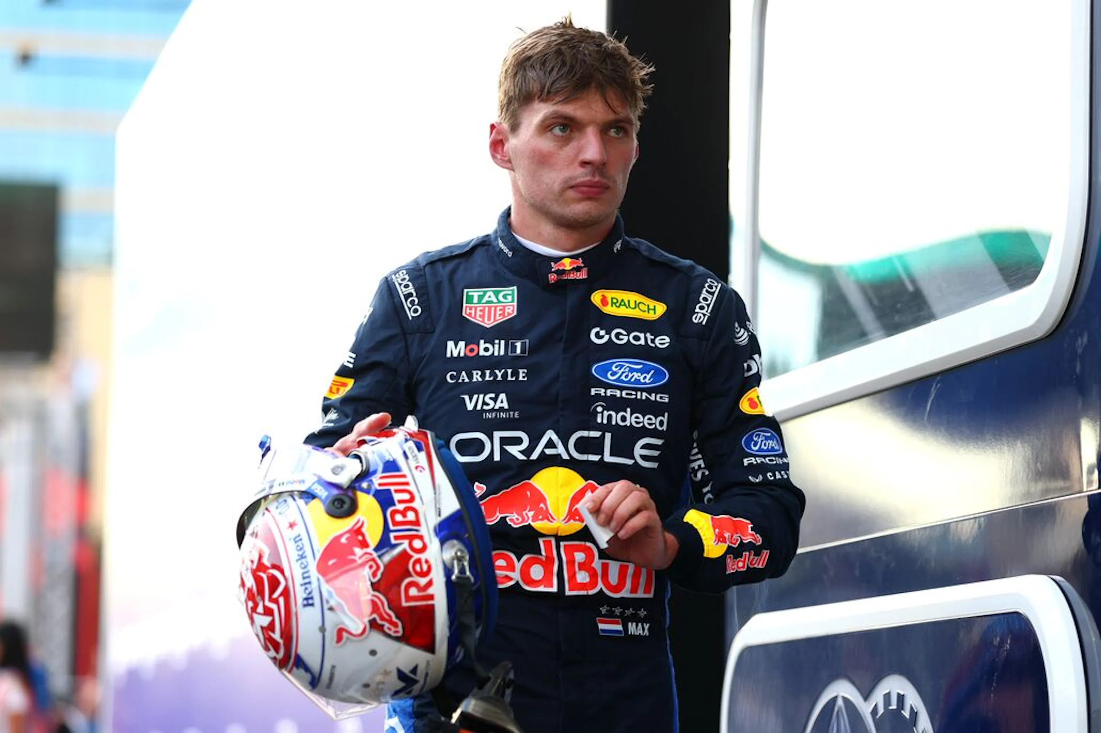 And F1 racer carries his helmet looking forward and serious