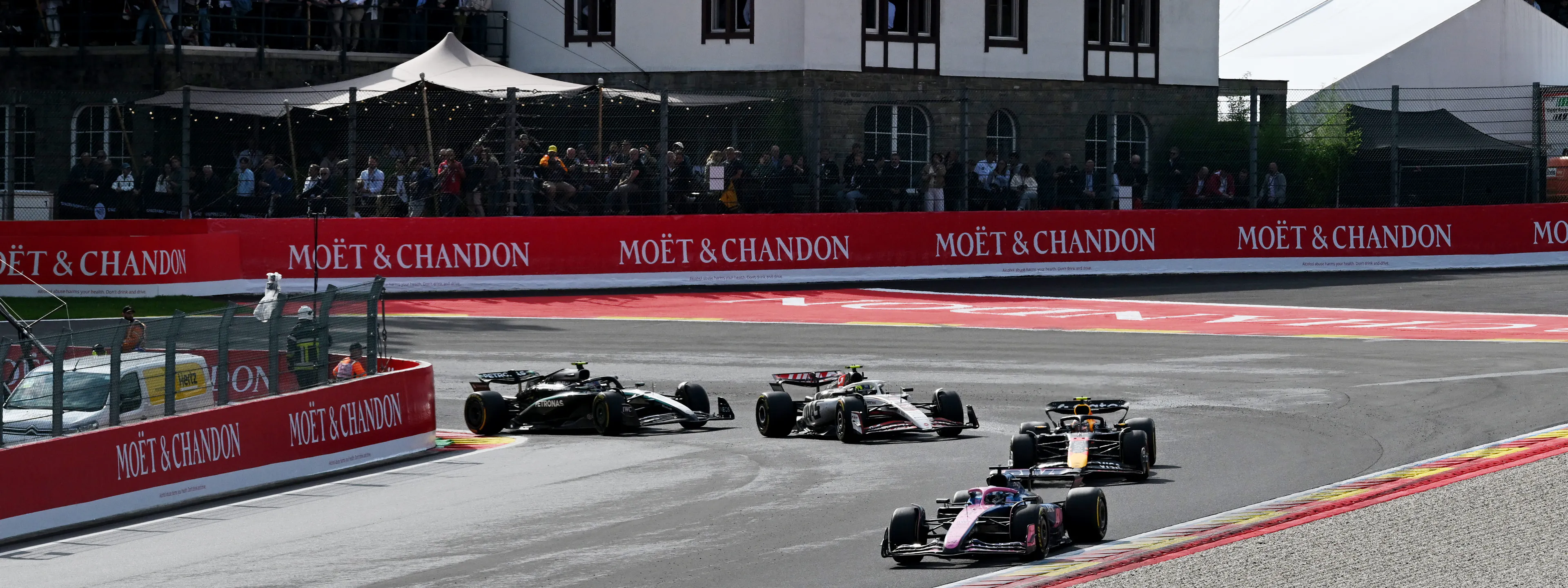 4 F1 racecars are taking a tight turn on a race track
