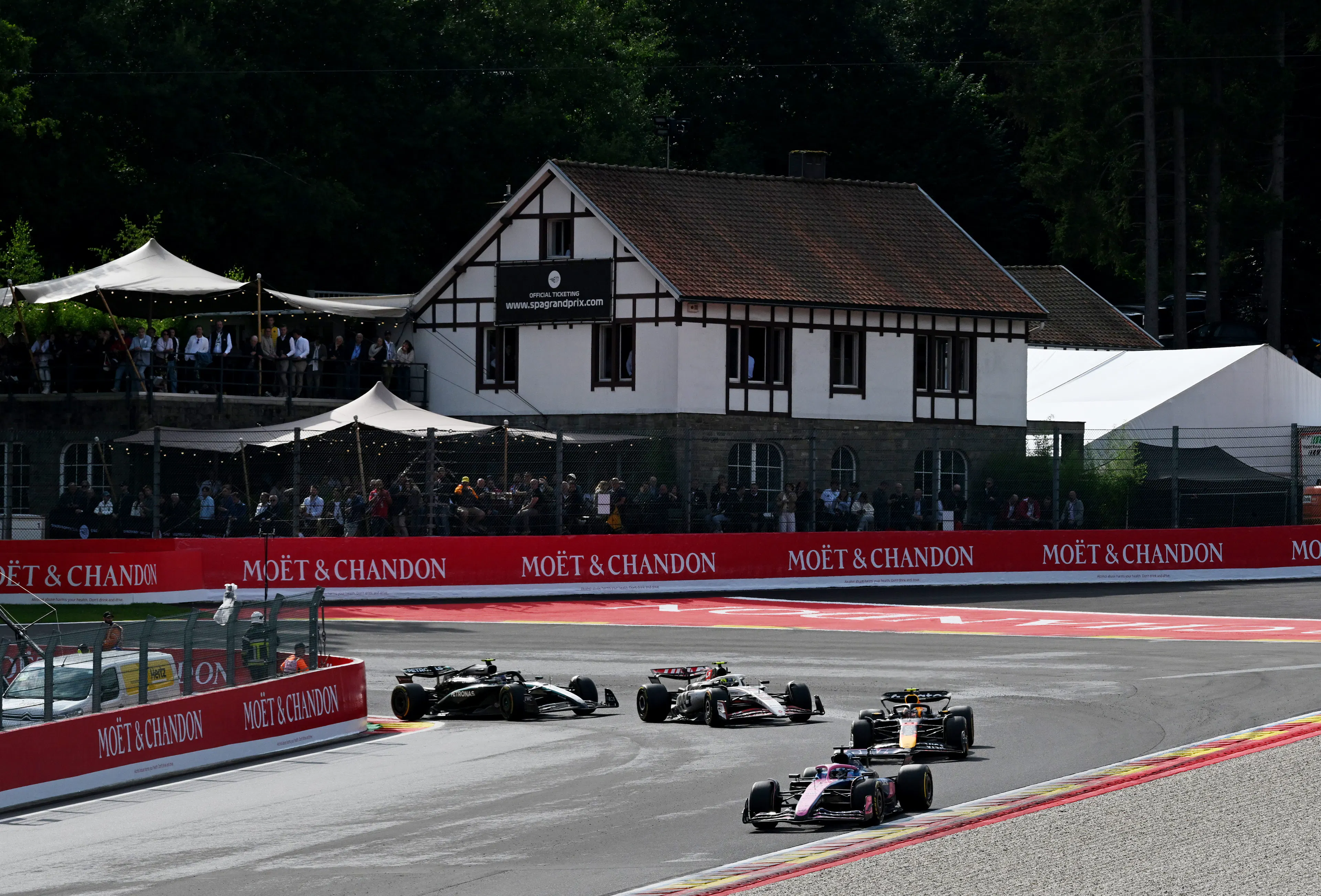 4 F1 racecars are taking a tight turn on a race track