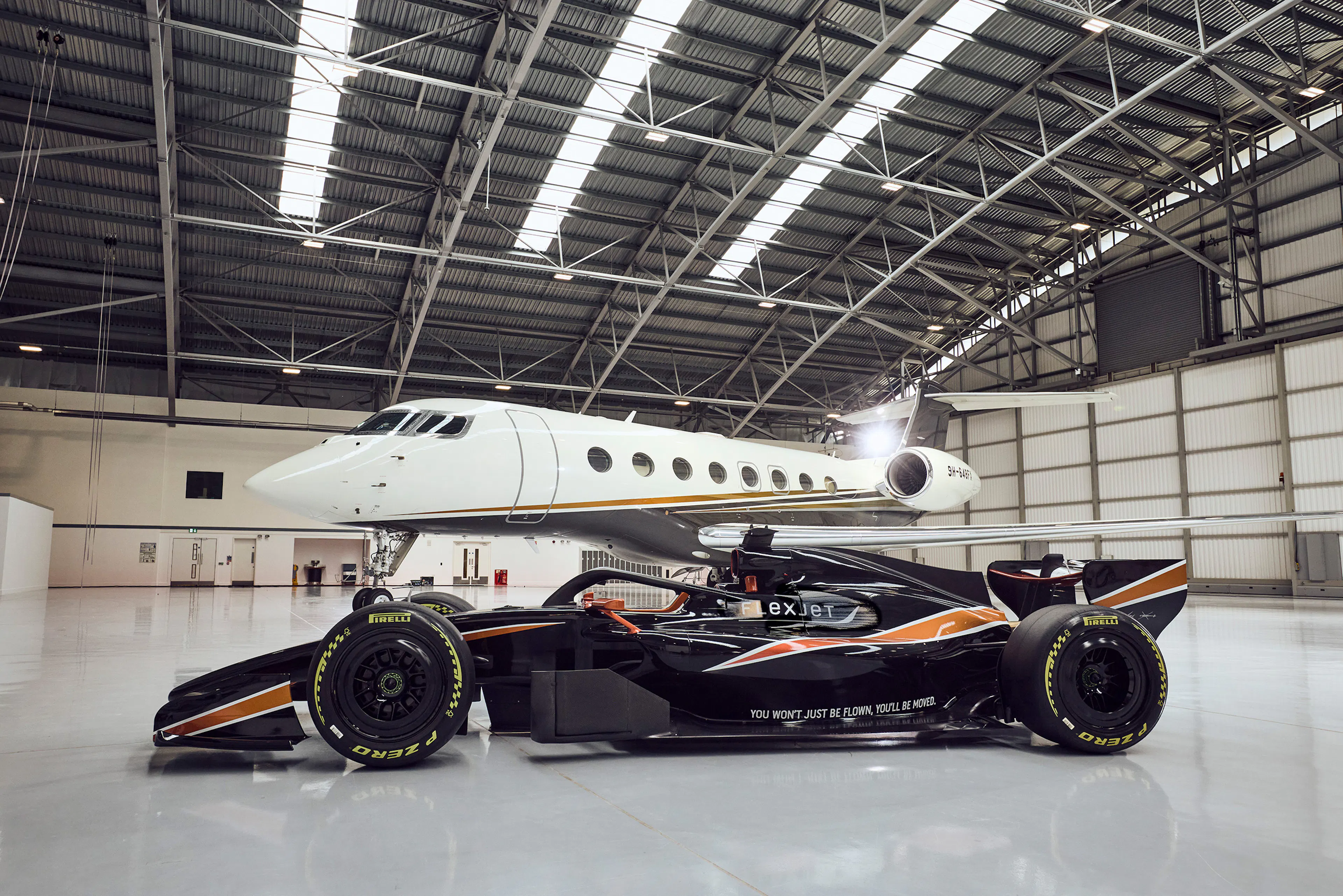 A Flexjet Branded racing car in front of a private jet in a hanger