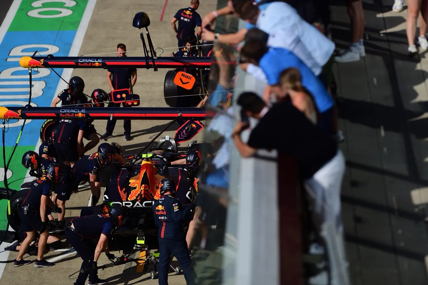 fans overlooking the pit crew working on an f1 car