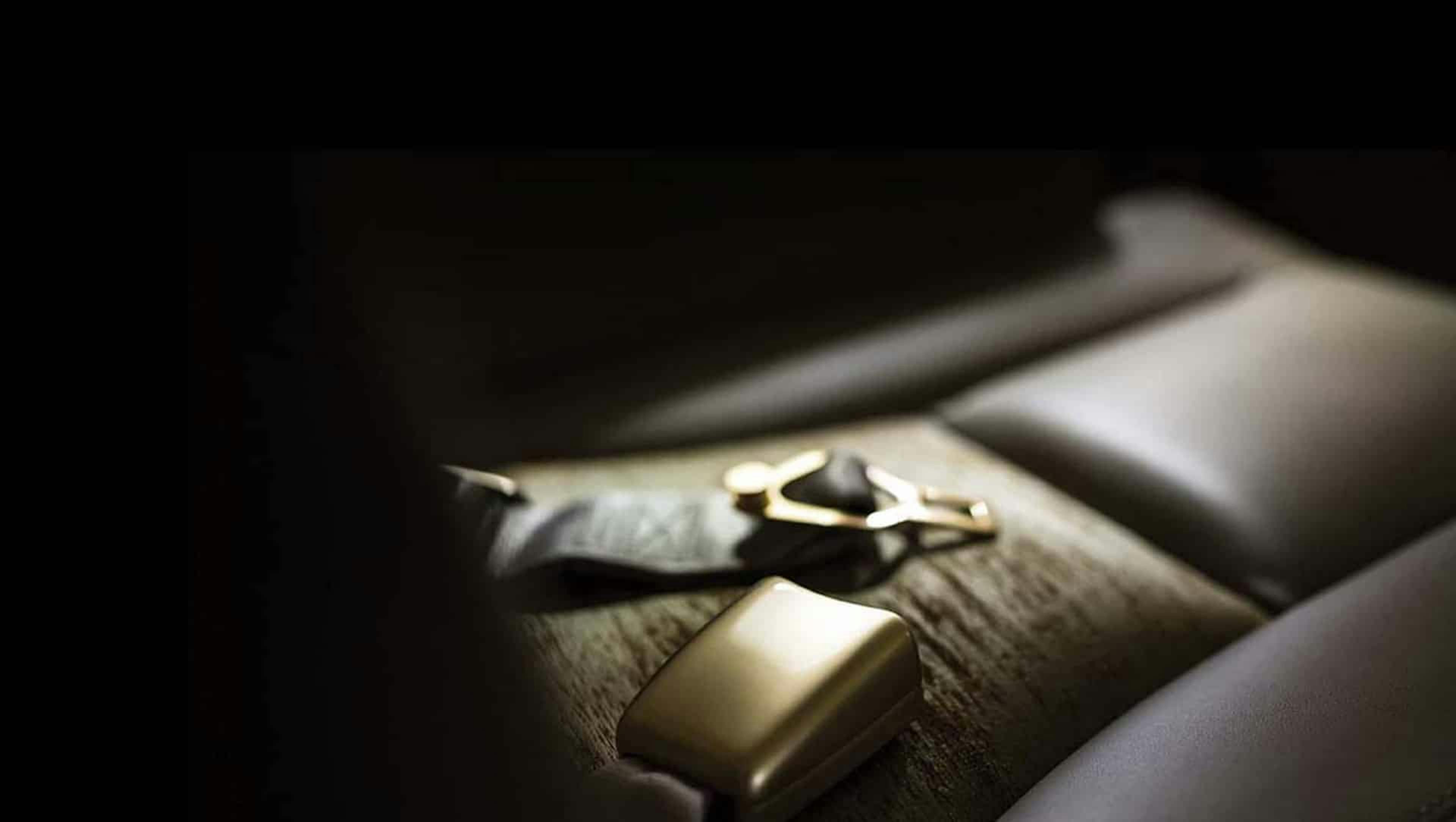 The seatbelt of an aircraft sits in defuse lighting unbuckled on the seat