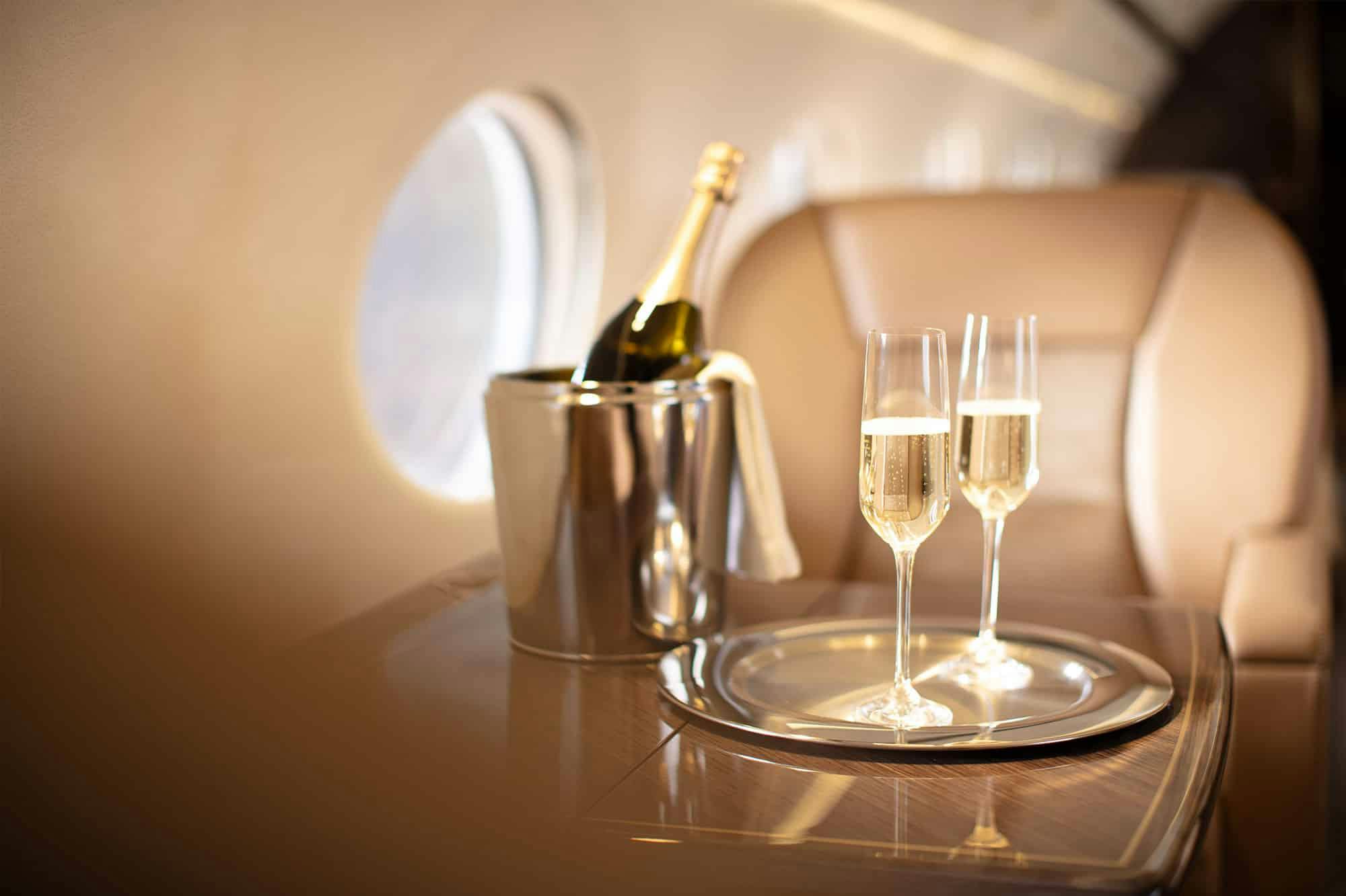 Champagne chilling in a silver bucket with bubbling glasses nearby silver plate.