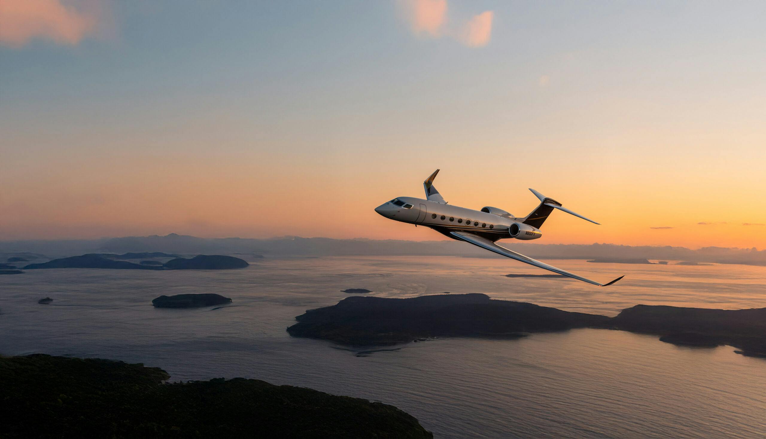 A flexjet aircraft flies, tilting left, over a bay with a golden band of light on the horizon