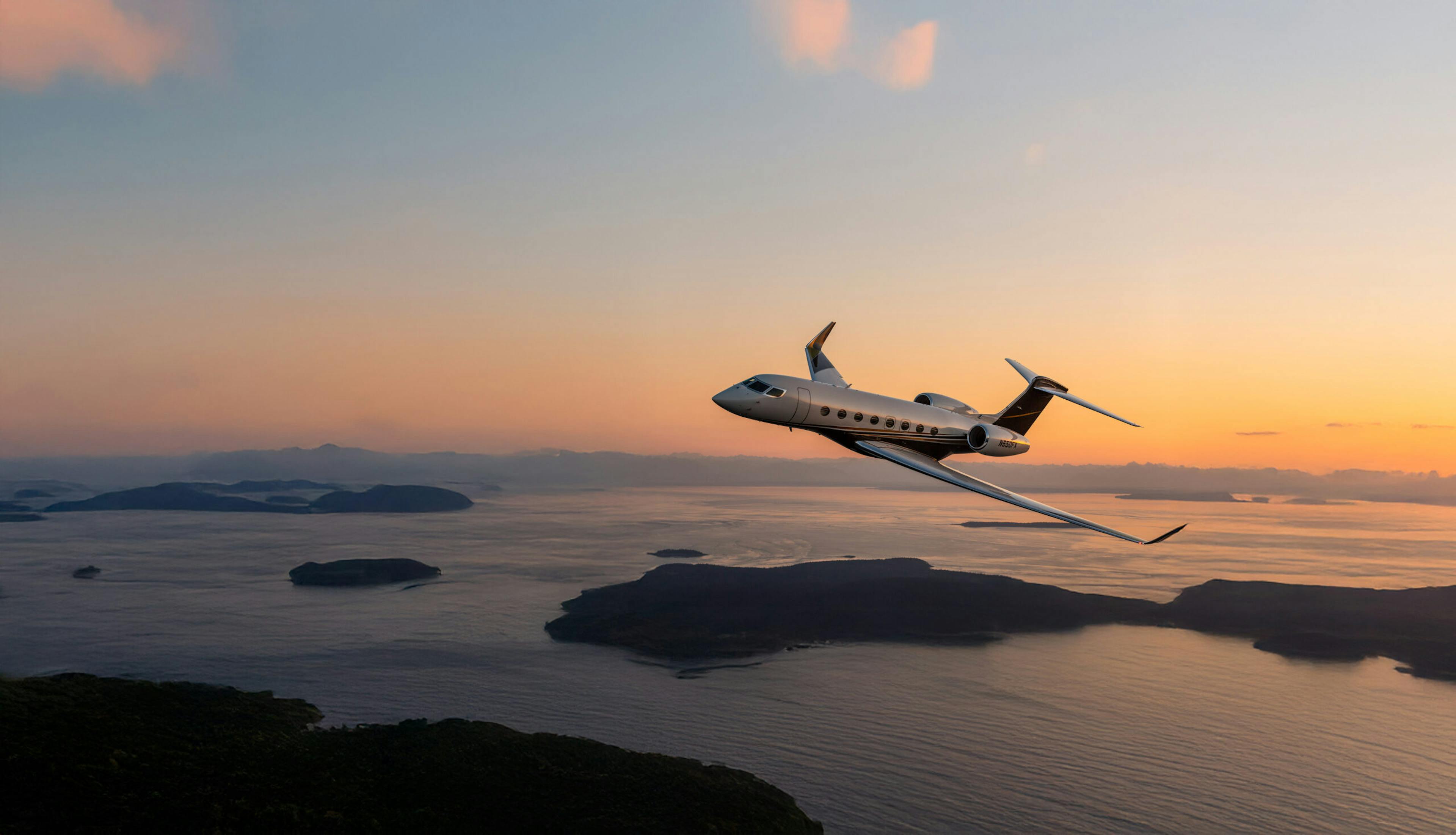 A flexjet aircraft flies, tilting left, over a bay with a golden band of light on the horizon