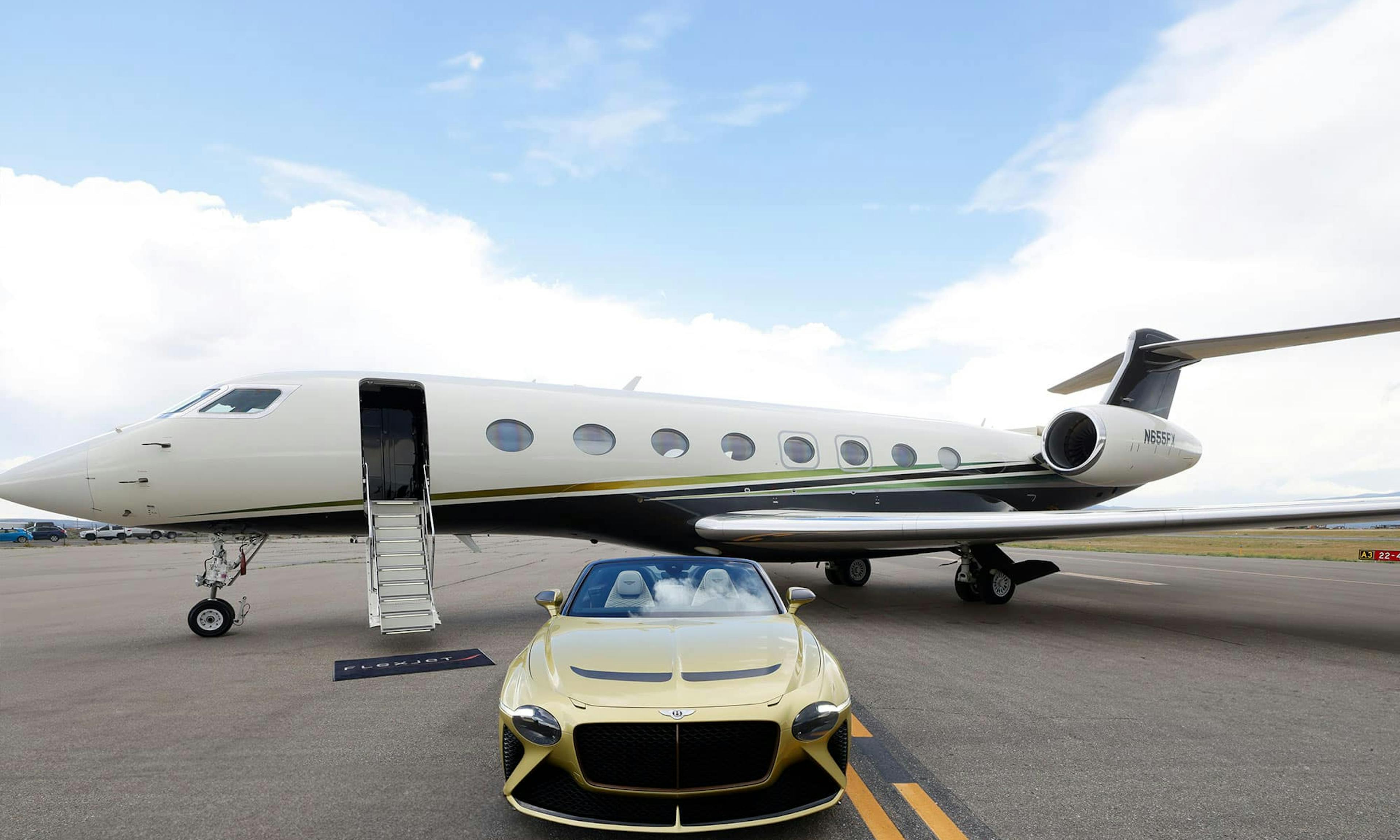 A golden Bentley sits outside a flexjet aircraft on the tarmac with its stairs down and flexjet mat at the base
