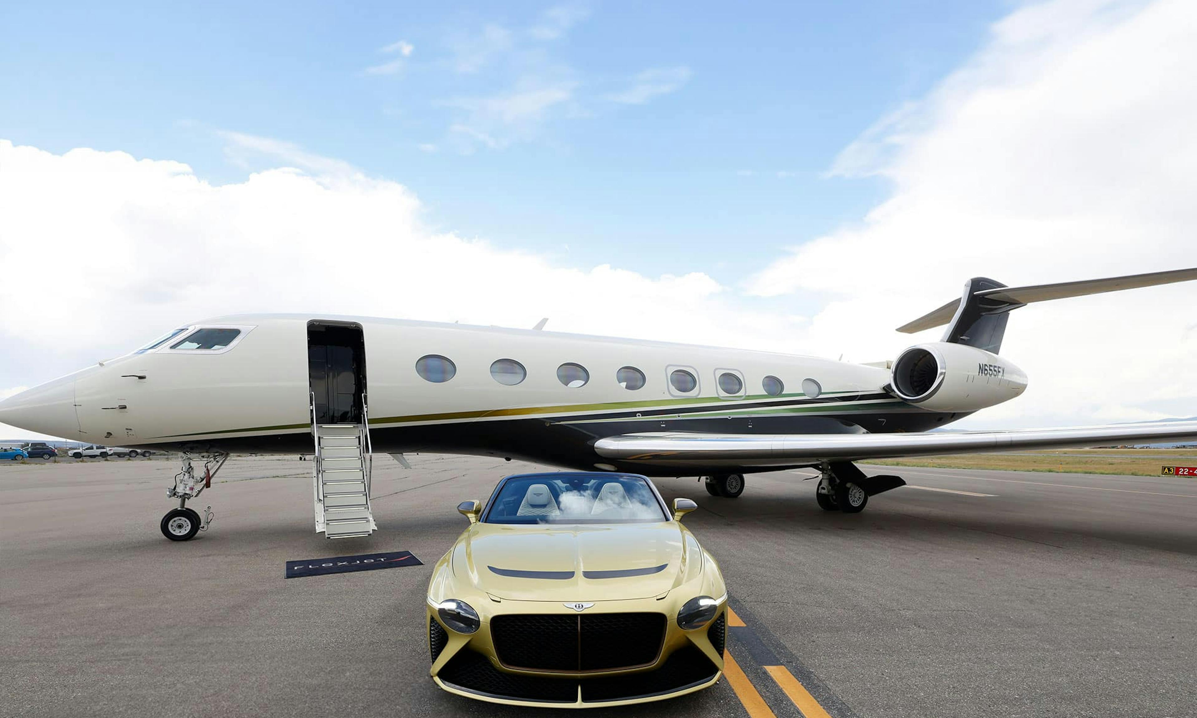A golden Bentley sits outside a flexjet aircraft on the tarmac with its stairs down and flexjet mat at the base