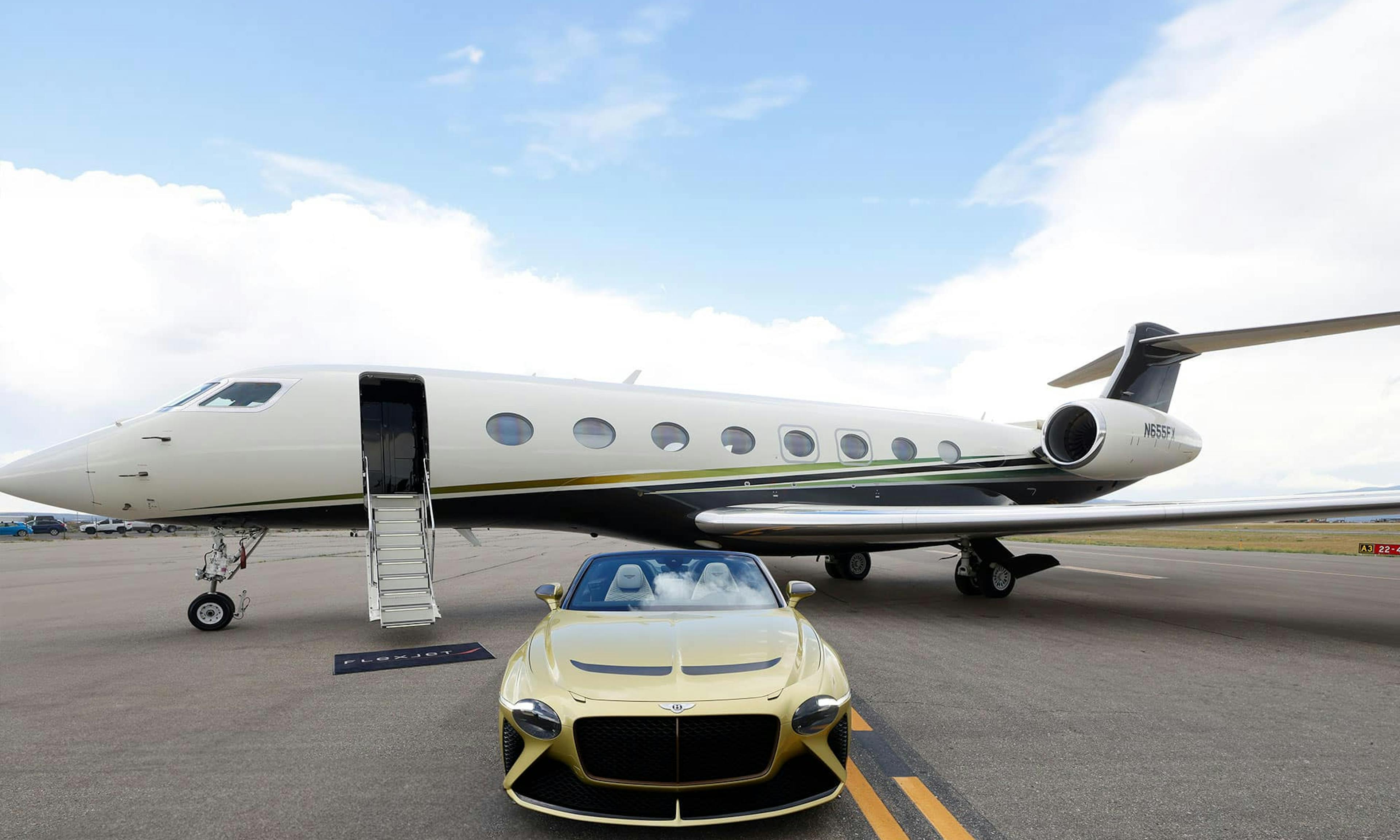 A golden Bentley sits outside a flexjet aircraft on the tarmac with its stairs down and flexjet mat at the base