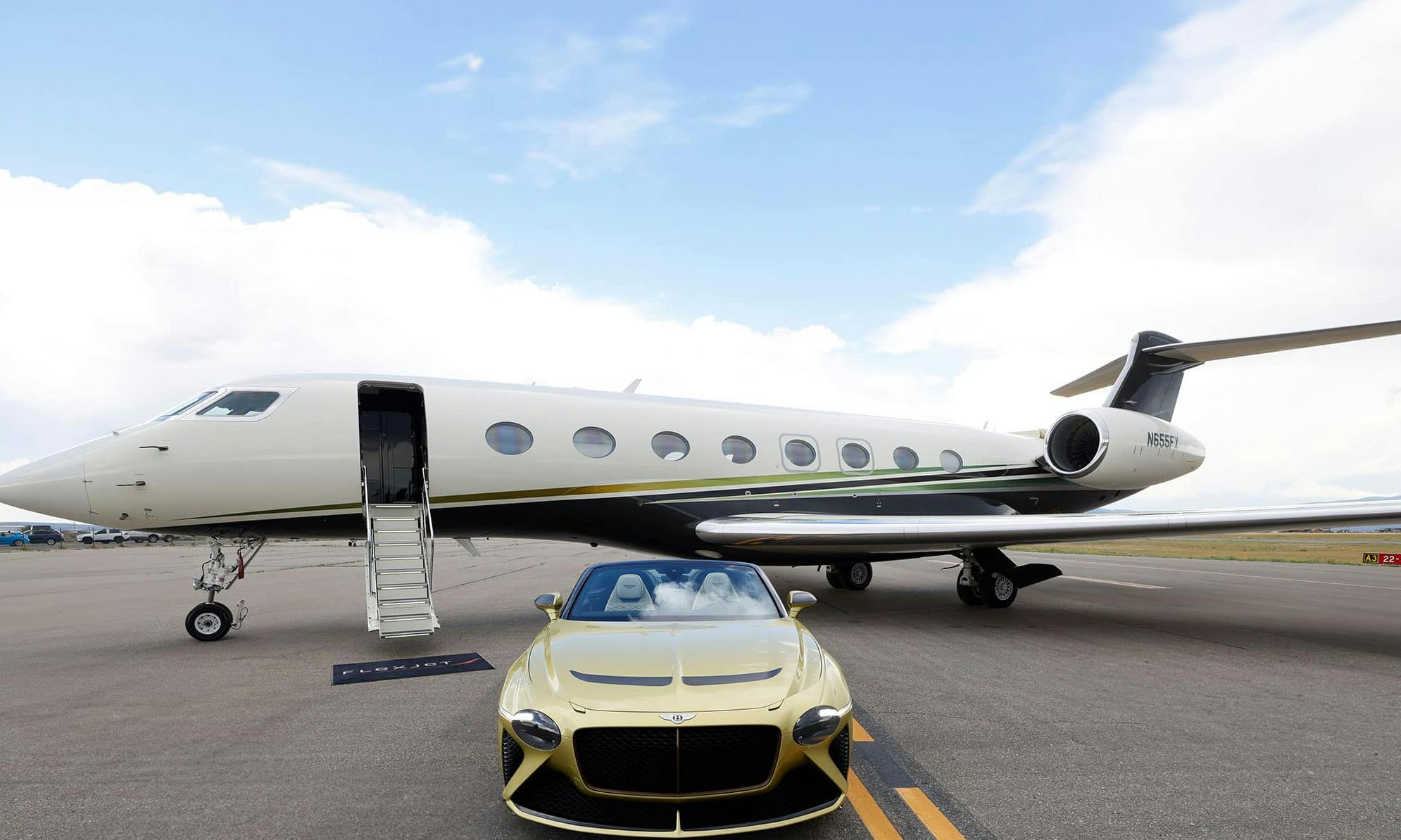 A golden Bentley sits outside a flexjet aircraft on the tarmac with its stairs down and flexjet mat at the base