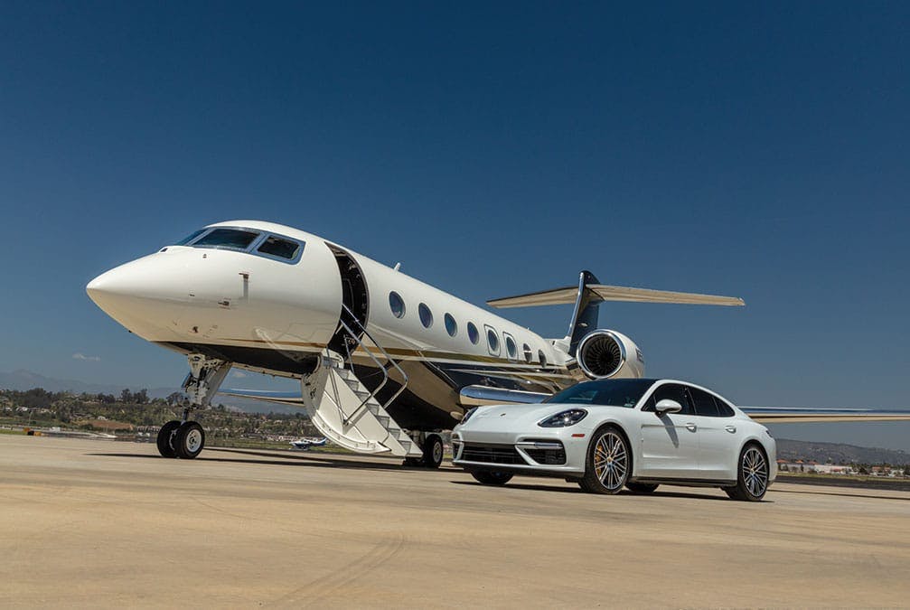 A porche is parked at the base of a flexjet aircraft with stairs down