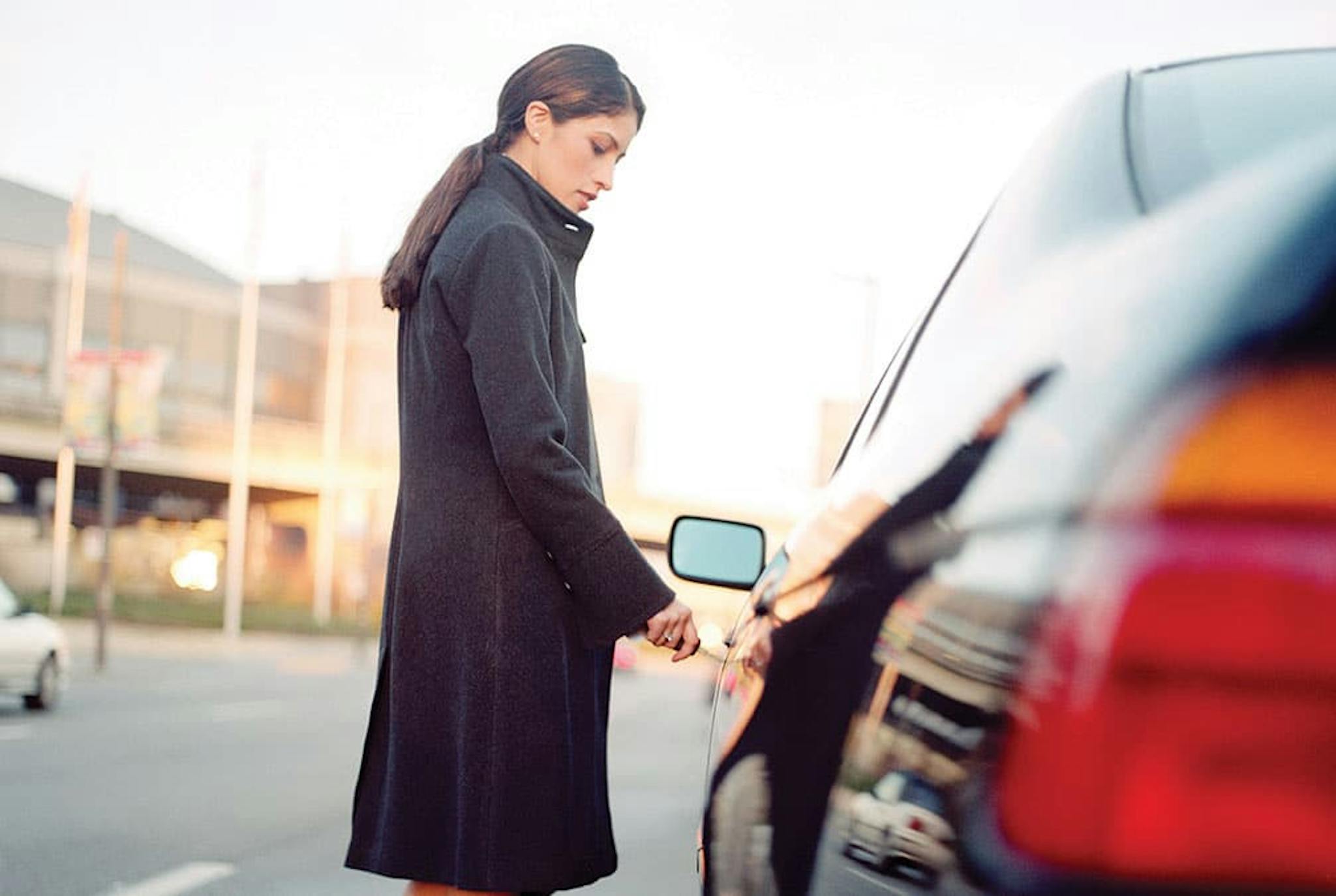 a woman inputs her key into the driver side door of her car