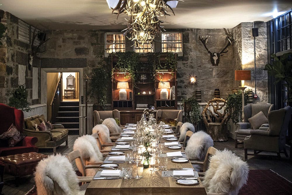 Cozy and dark interior dining table with furs draping over the seats