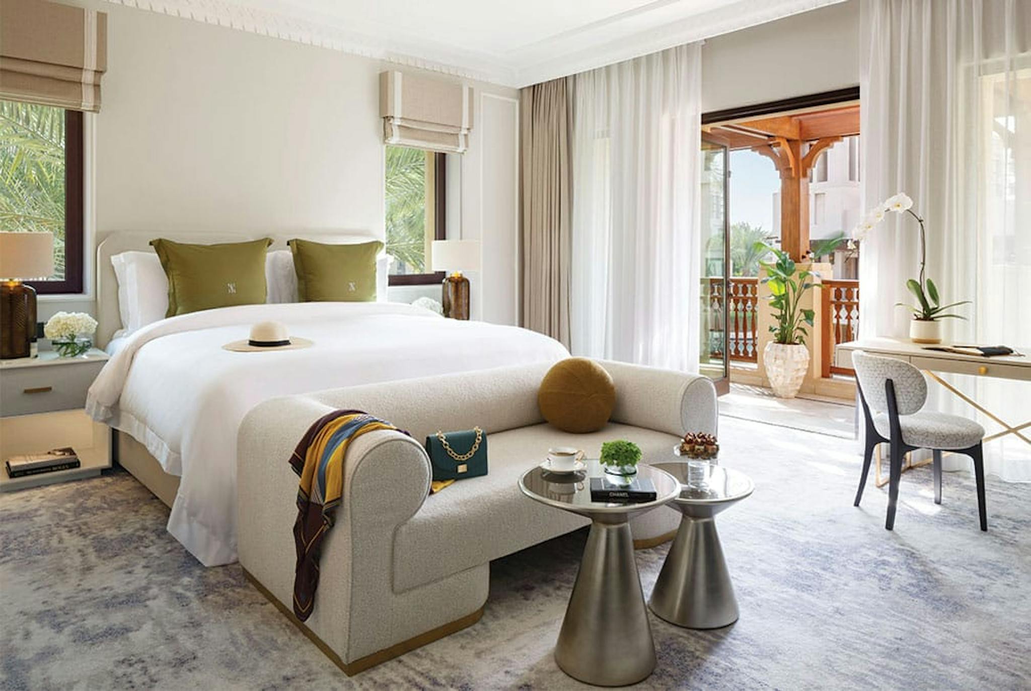 White linen bed with green pillows and elegant room with balcony