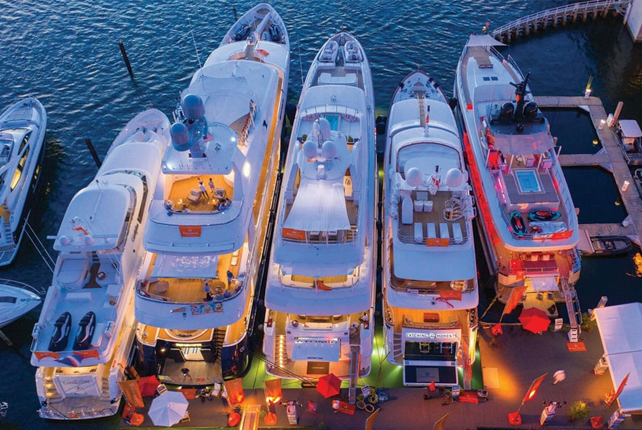 Boats backed into a dock at twilight with lights and festive colors