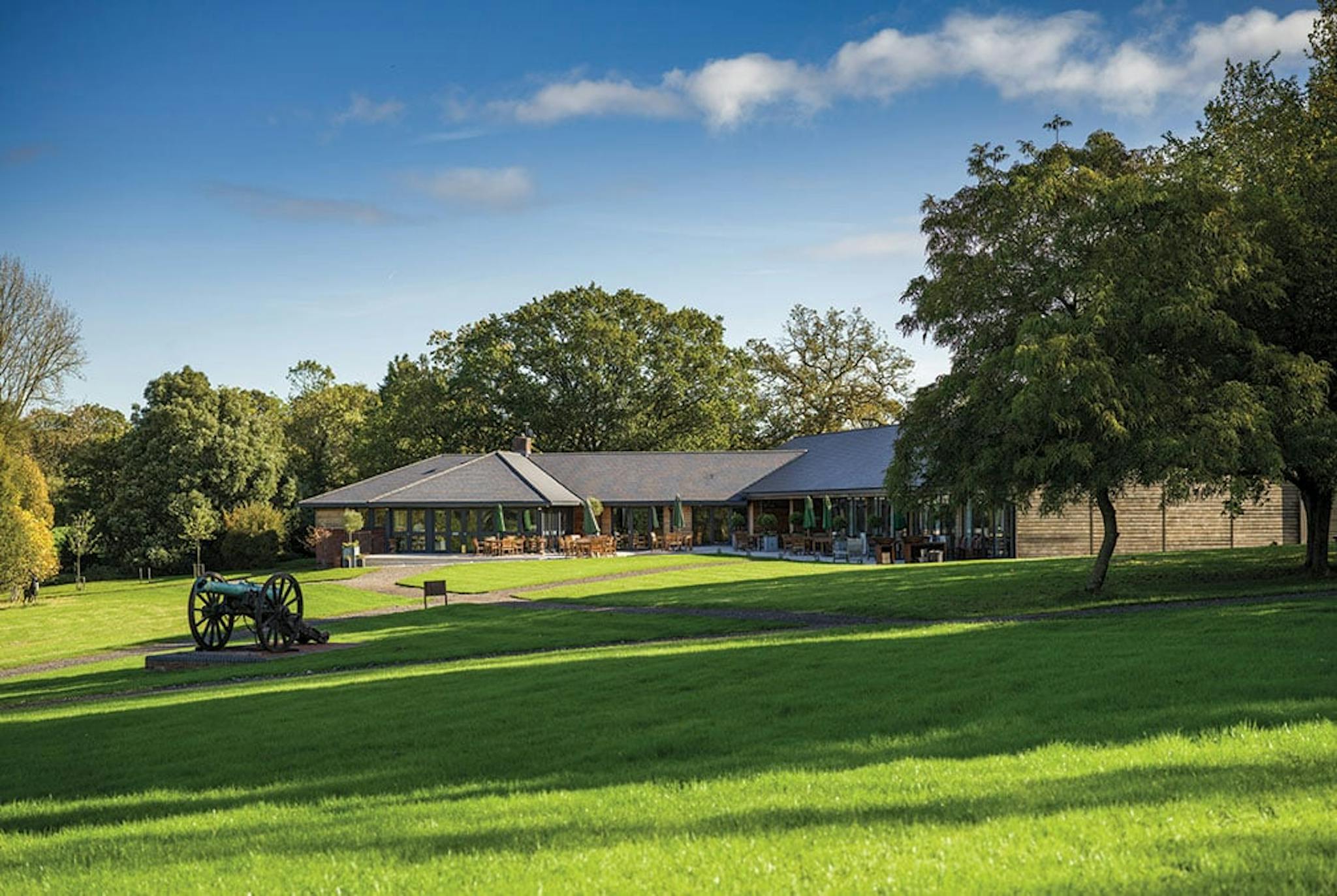 green field with historic canon out behind a wide building