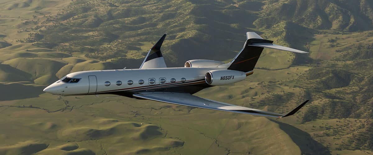 A flexjet aircraft flies over green rolling hills