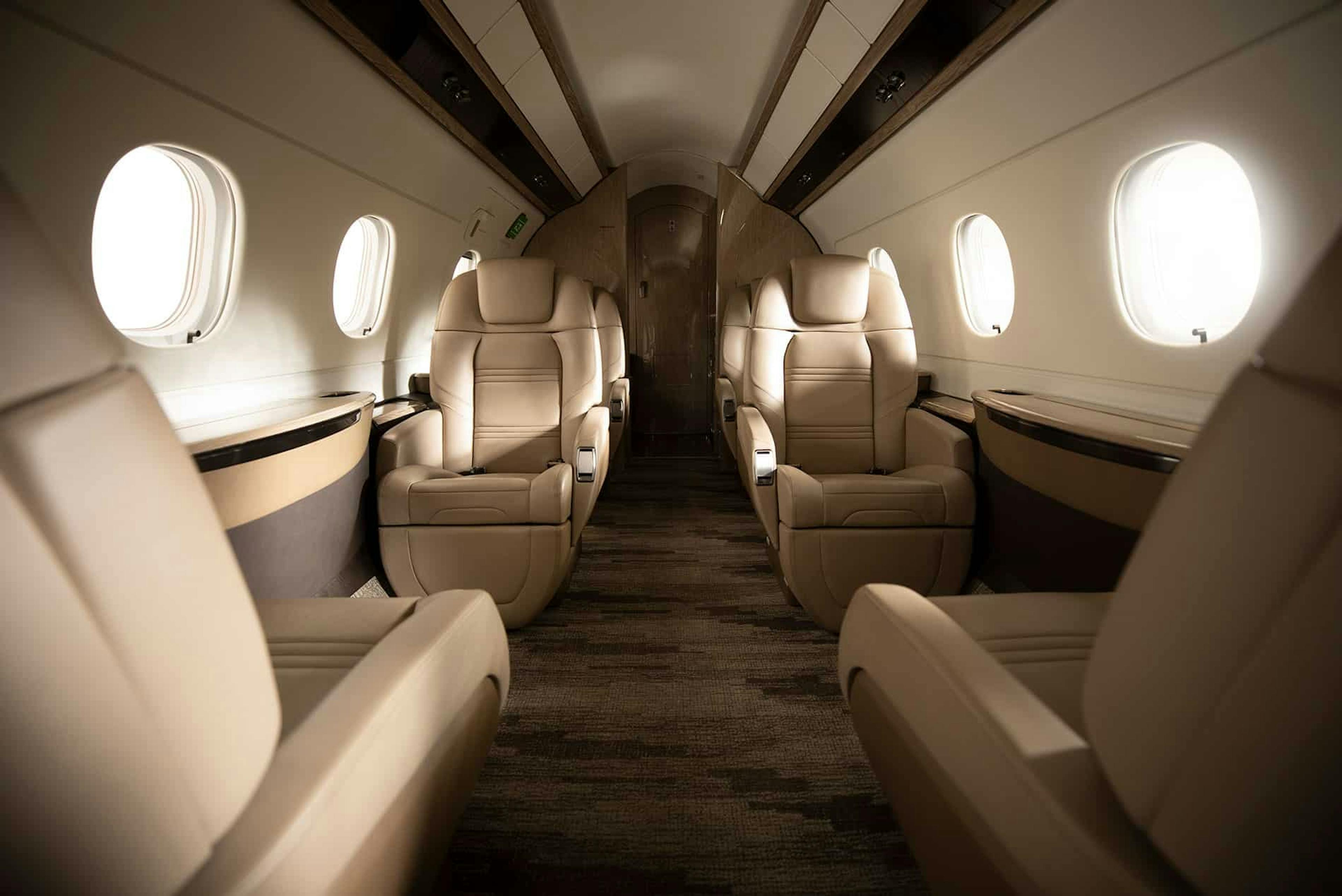 luxury interior of the praetor 500, with tan leather seats, custom carpet and light illuminating the rounded windows