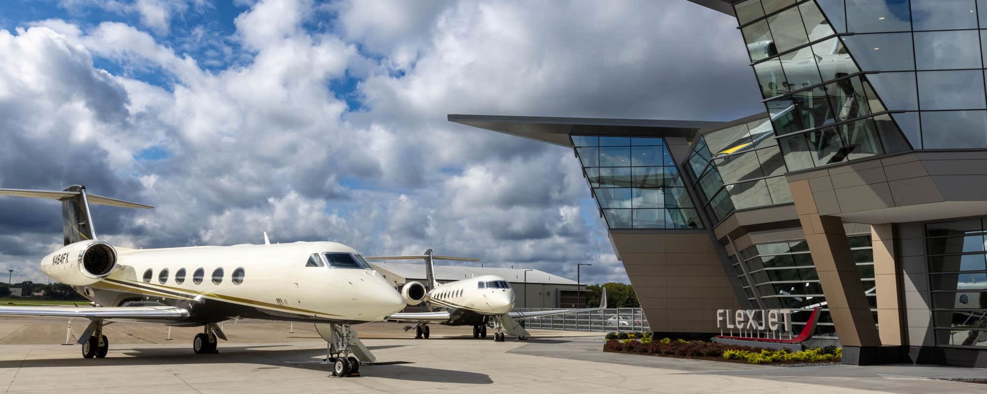 Two flexjet aircraft sit outside the headquarters of flexjet on a cloudy day