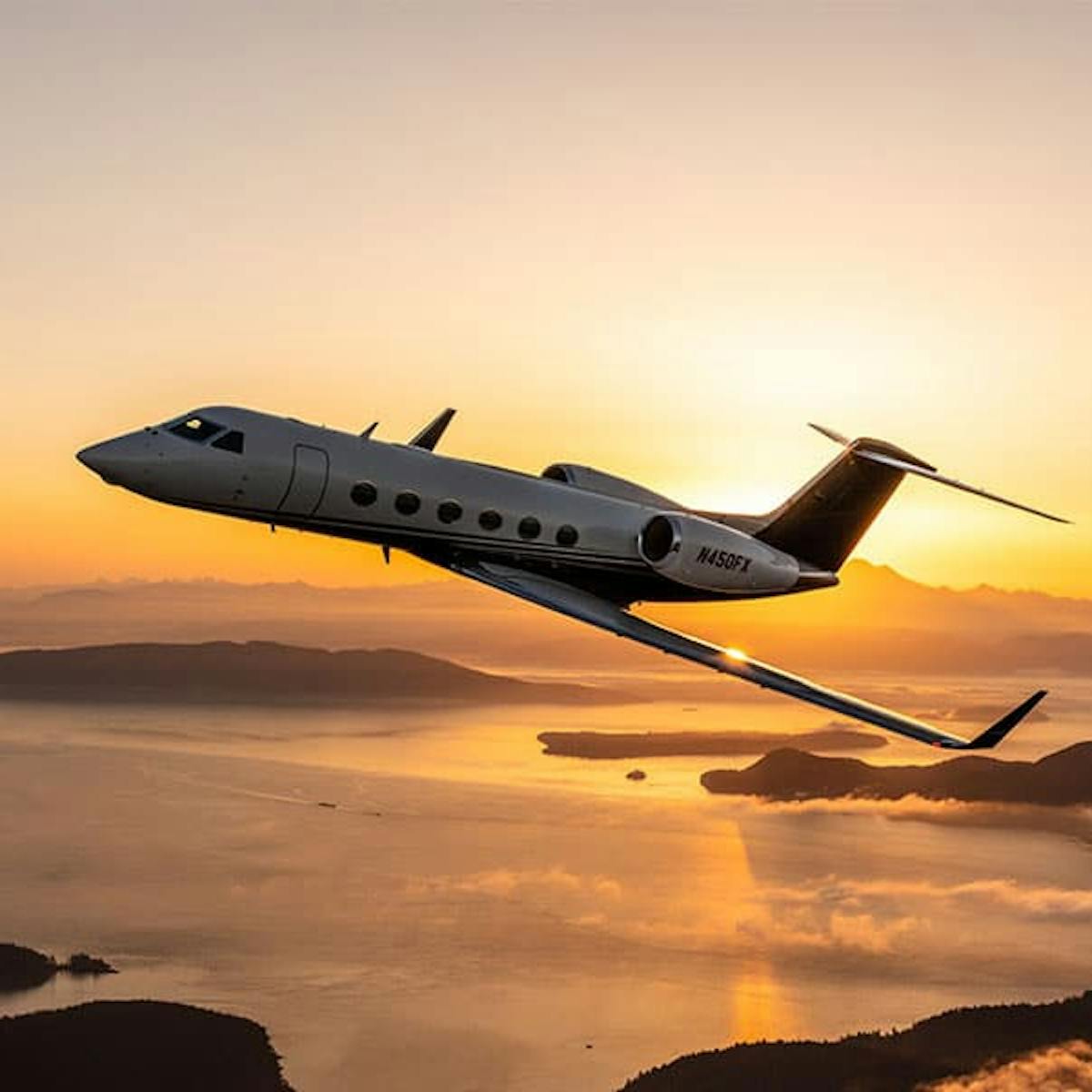 G450 flies over yellow sunset shining on glossy waters and rocky inlets