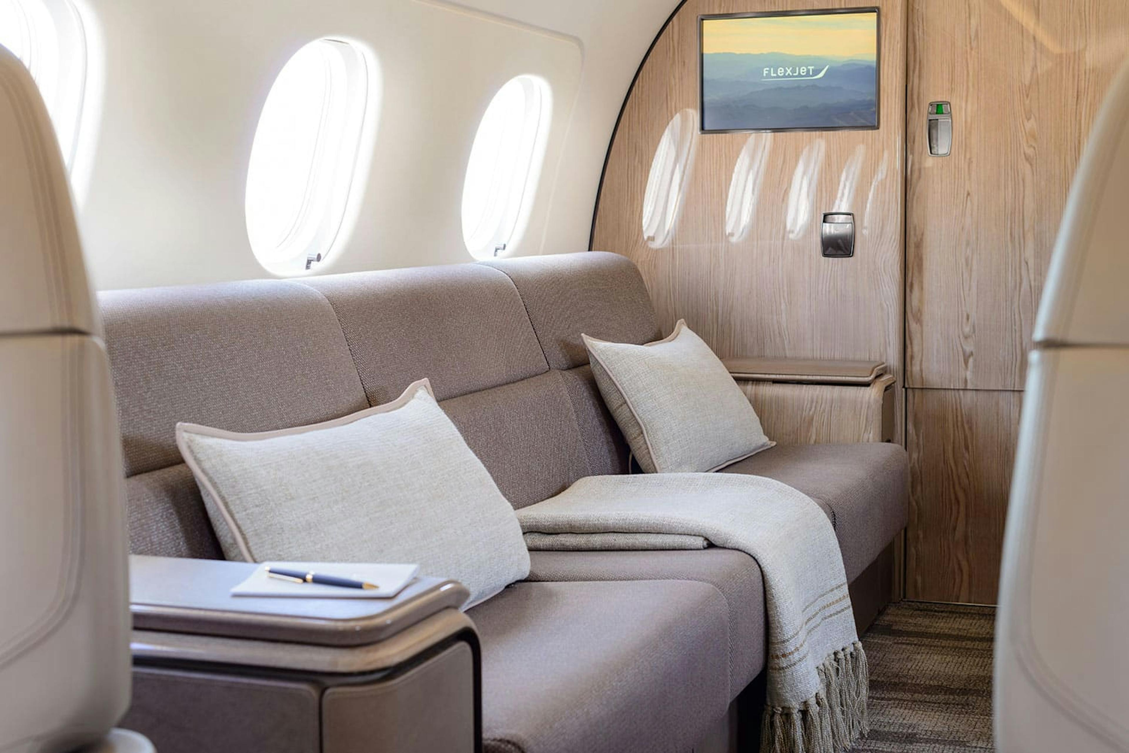 focus on a couch in the center of the plane with white pillows and blanket flowing over the edge