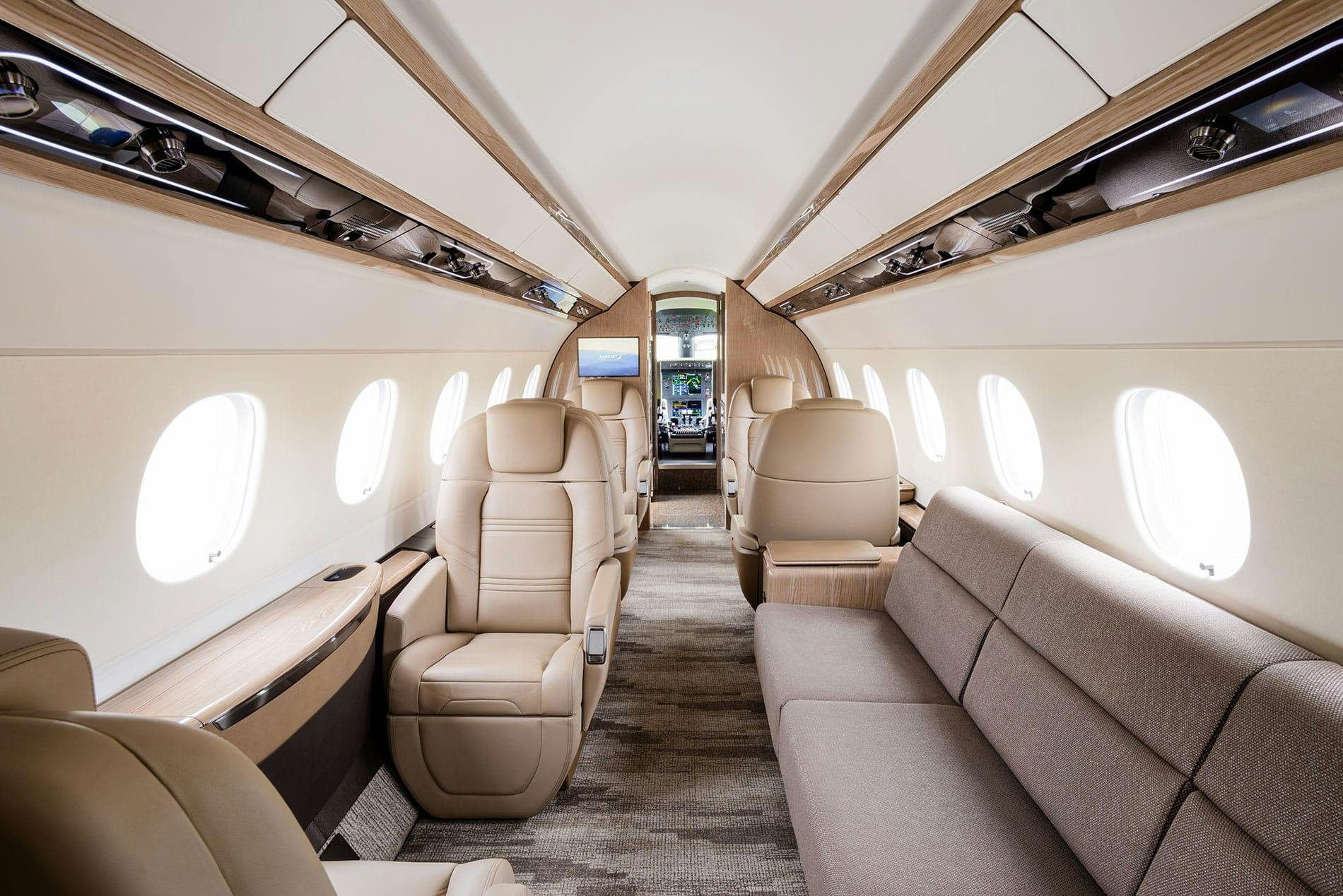 Fancy interior of jet with white and light tan walls, ceiling and furniture highlighted with brown tones