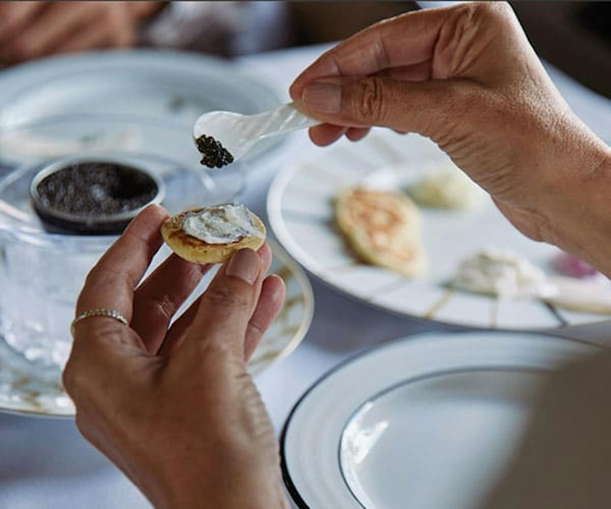 Hands placing caviar onto fancy cracker
