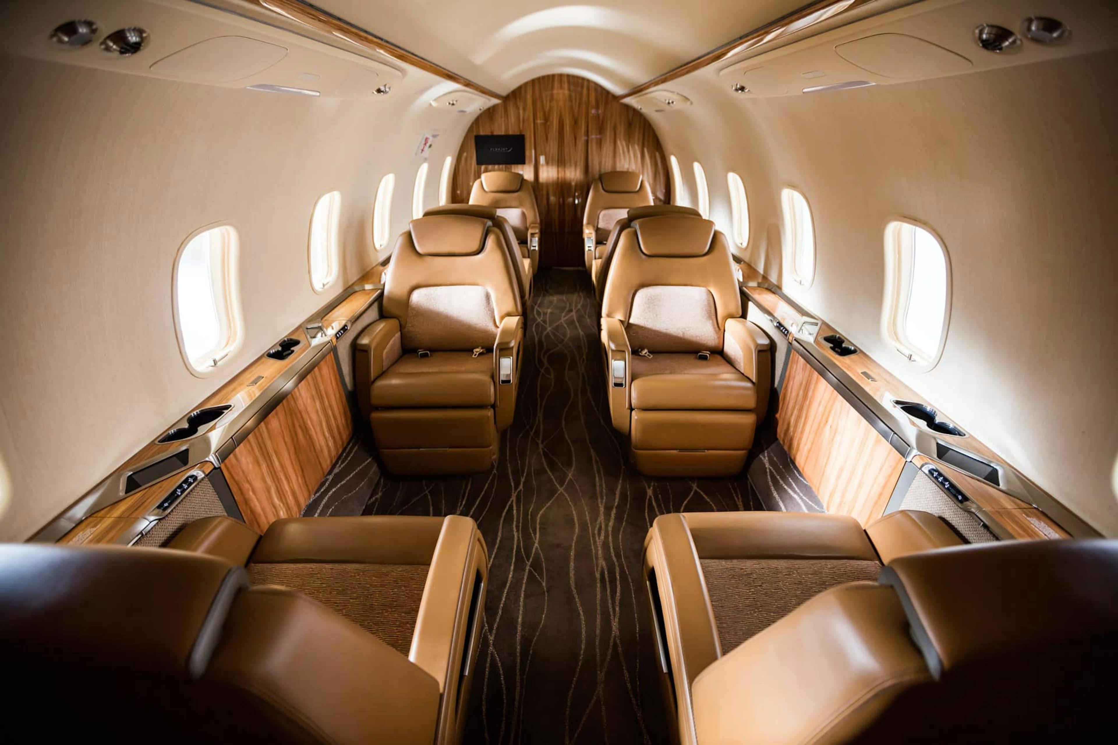 Luxury interior airplane cabin with tan leather seats, custom carpeting, and soft tones