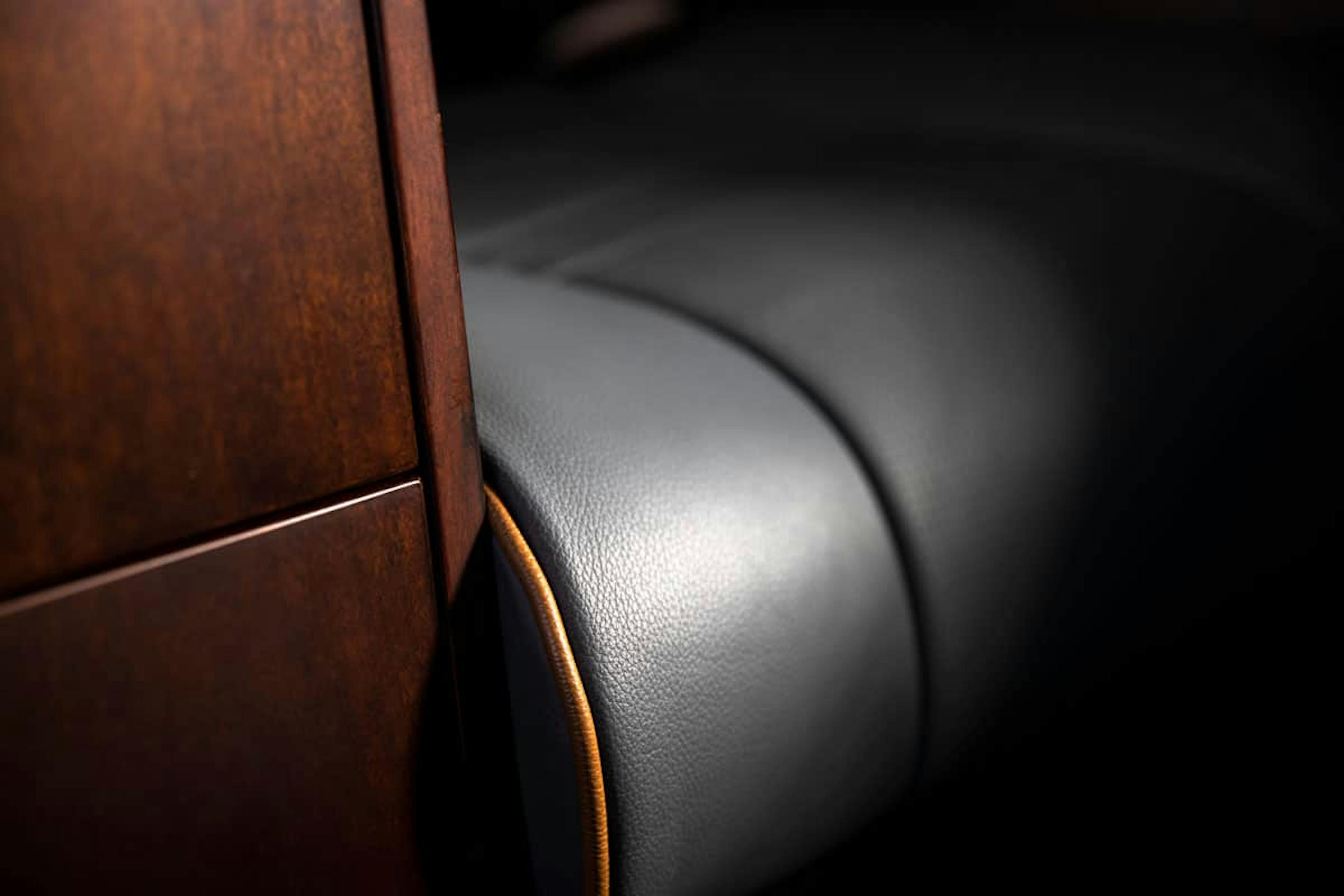 Up close focus on the seat material and dark wood arm rest