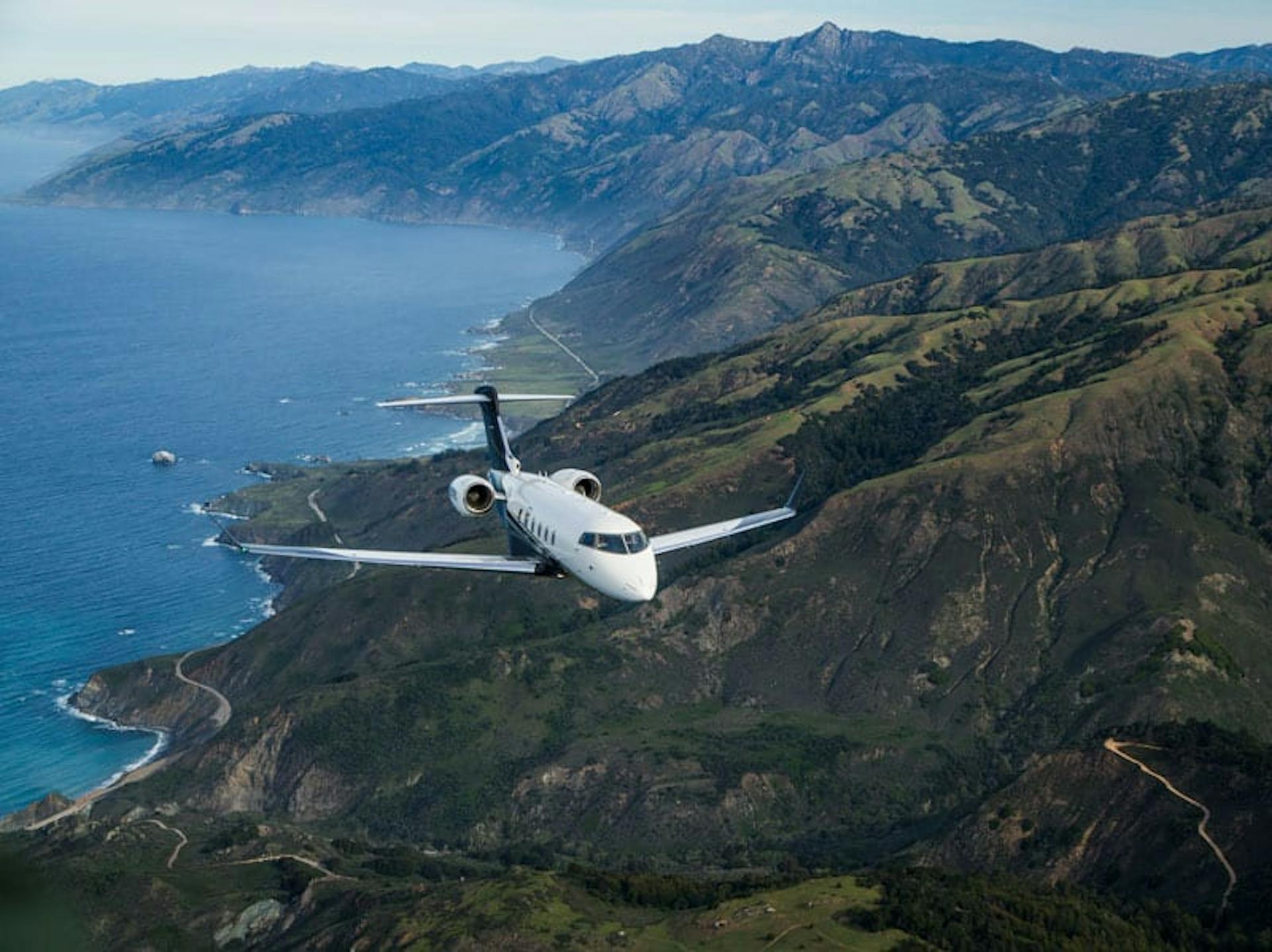 aircraft flying over mountains and ocean