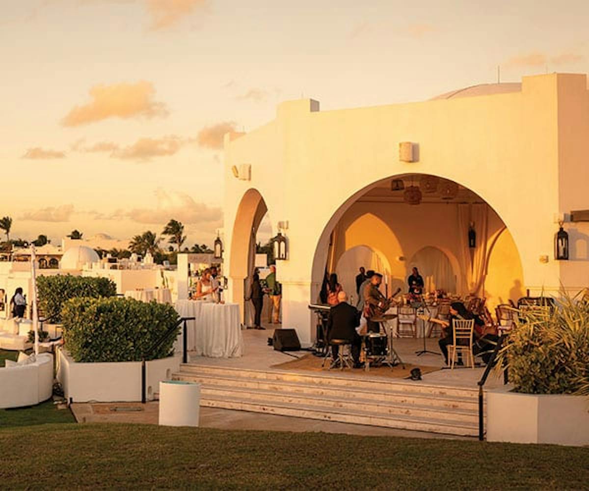 A band is set up outside with tables and white sofas for an event at a fancy location