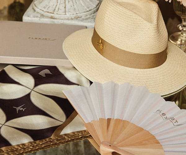 Custom Flexjet branded merchandise such as a hat, fan, and silk scarf.