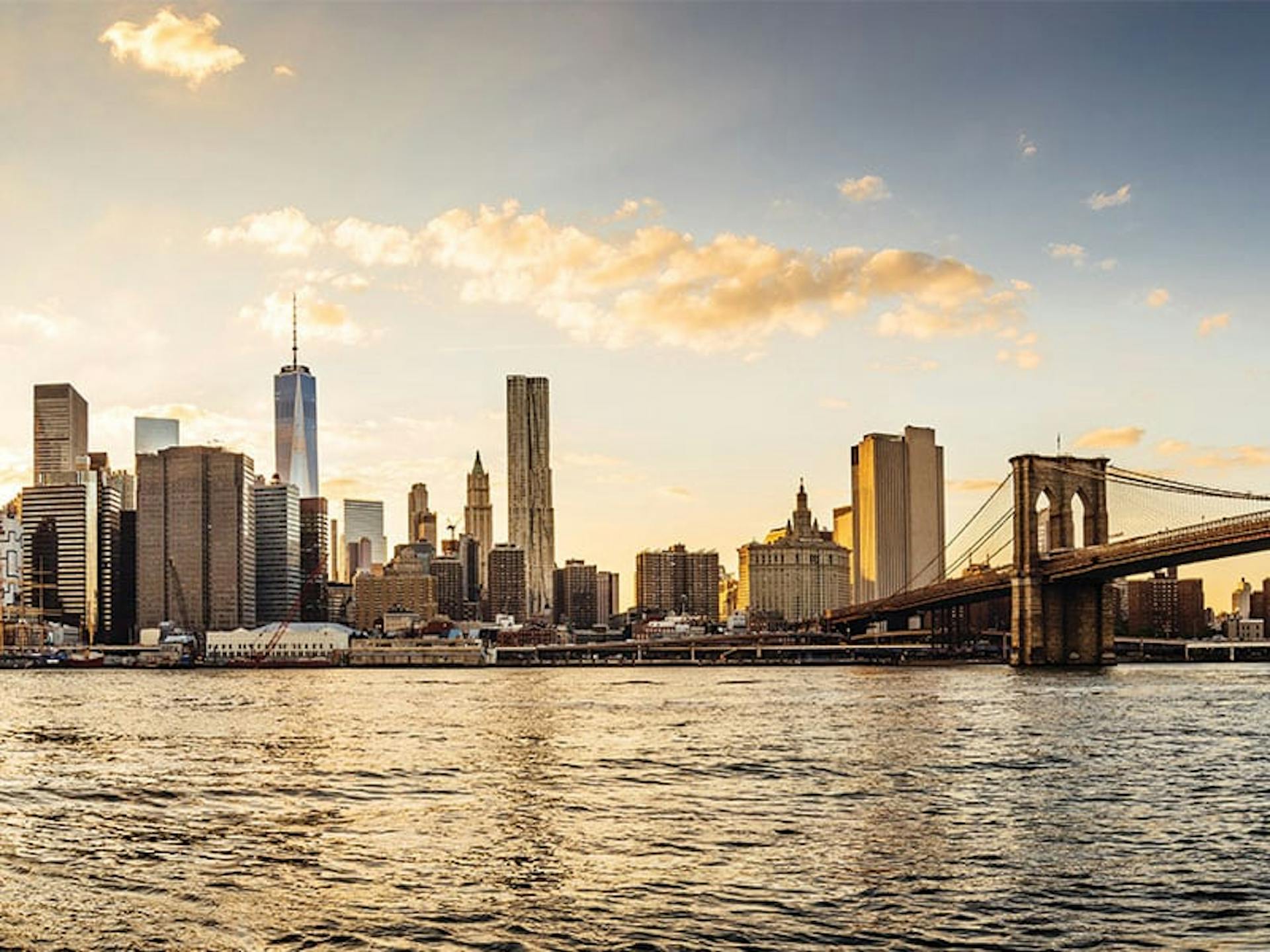 city skyline from the view of a body of water with a bridge off perspective on the right side