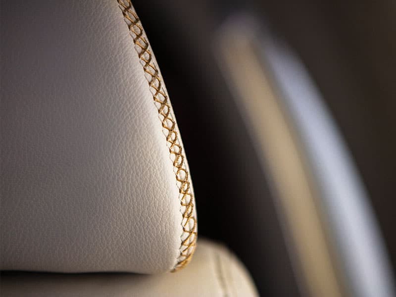 close up on the intricate stitching on the leather headrest of the seat on a luxury aircraft