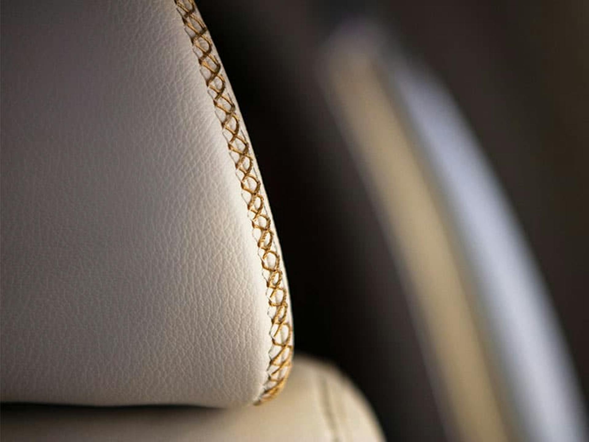 close up on the intricate stitching on the leather headrest of the seat on a luxury aircraft