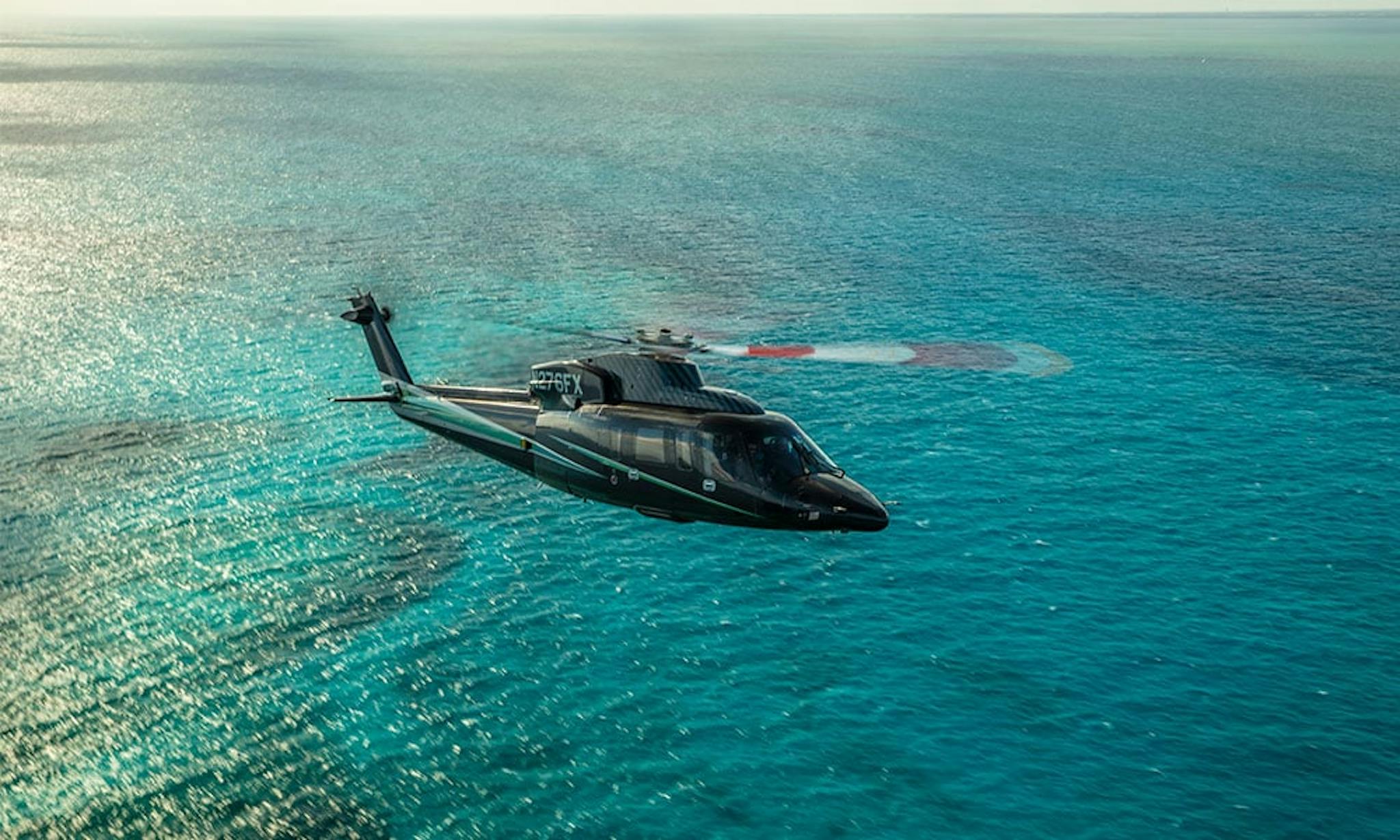 An s76 flies not far over turquoise blue waters