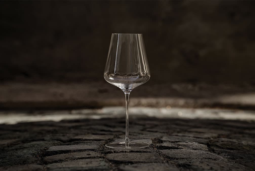 A wine glass sits outside in the dark on a stone path