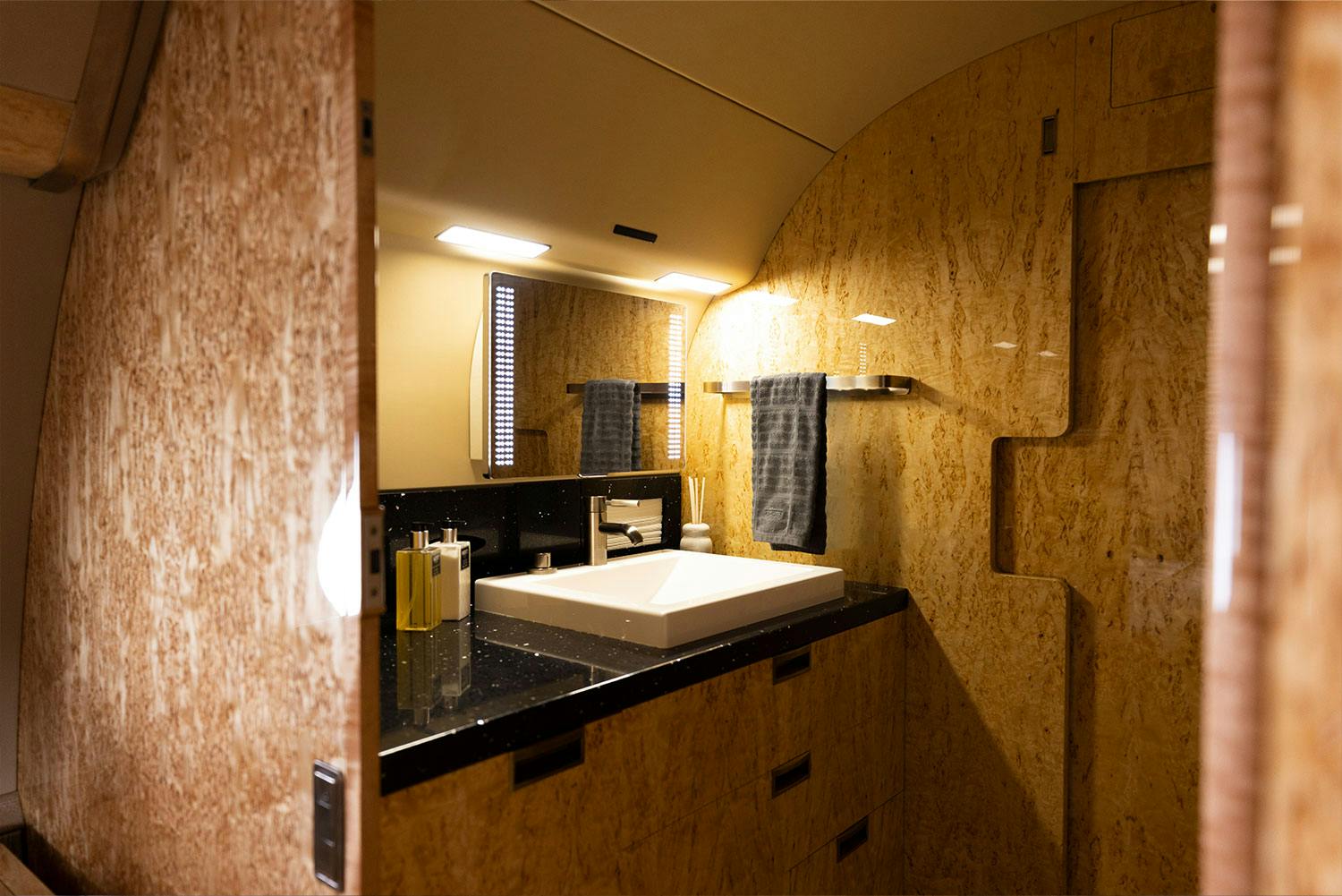 Luxury interior Capri inside a private jet focused on the big and bold bathroom with mirror and sink at the center