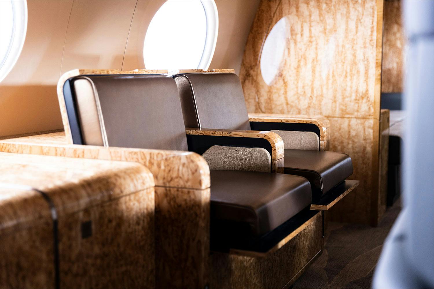 Luxury interior Capri inside a private jet focused on unique dark leather seats and light brown patterned paneling