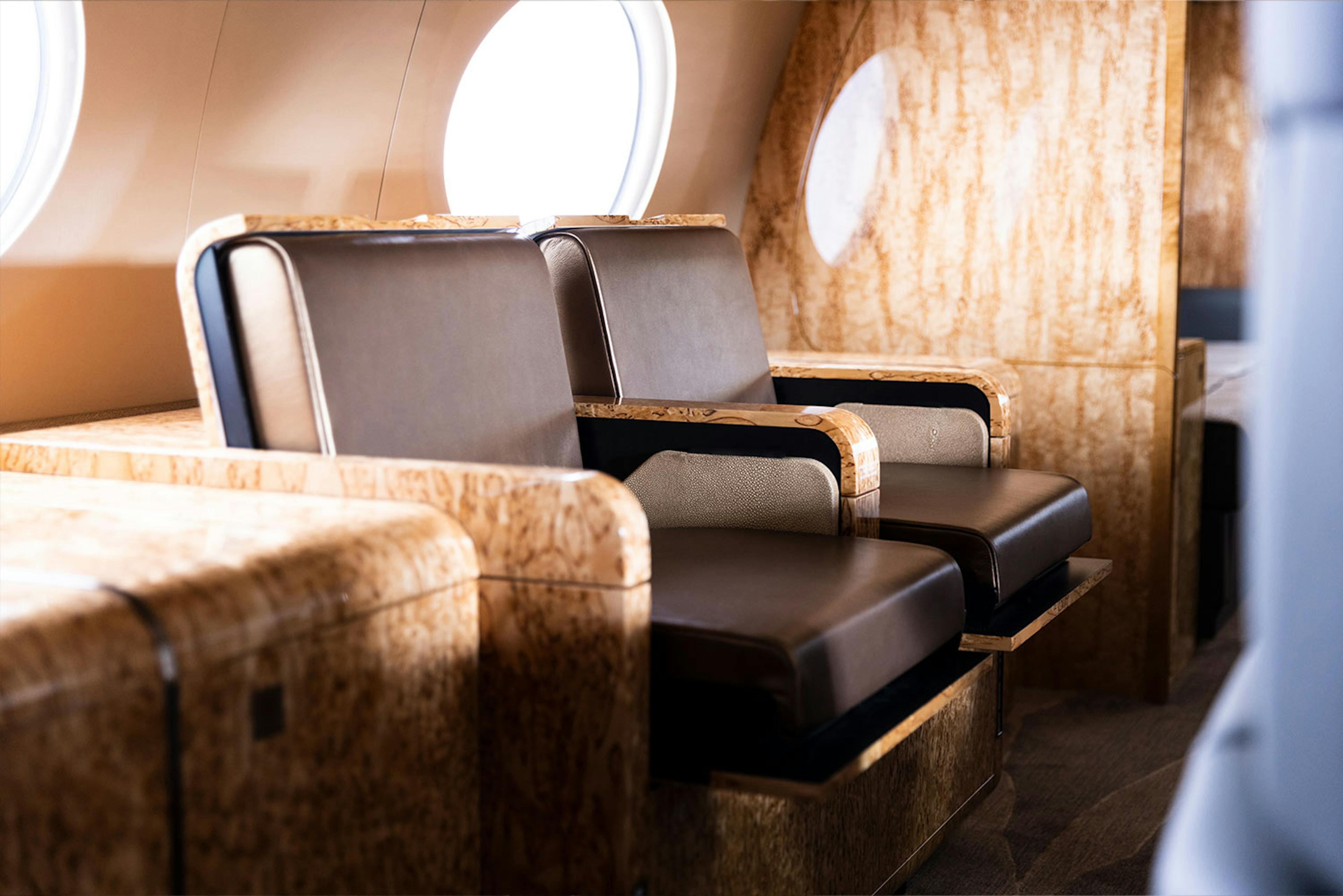 Luxury interior Capri inside a private jet focused on unique dark leather seats and light brown patterned paneling