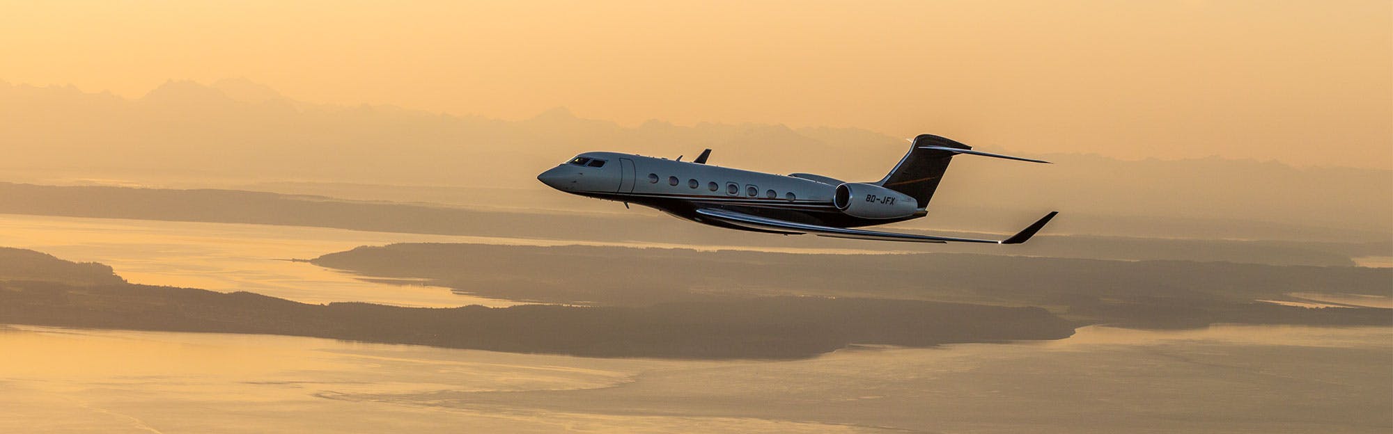 g650 flies above yellow cloudy skies and visible bay and water below