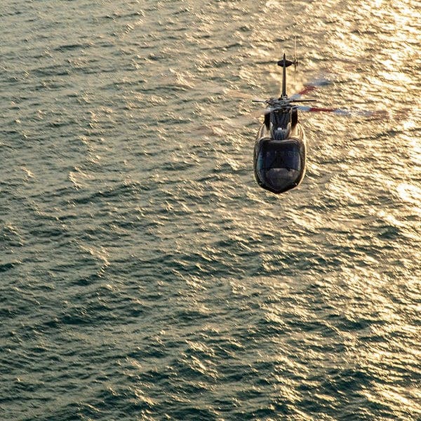 a flexjet helicopter flies over choppy waters