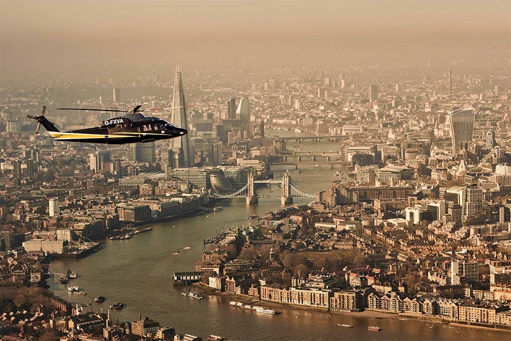 s76 flies over a dense city along a river