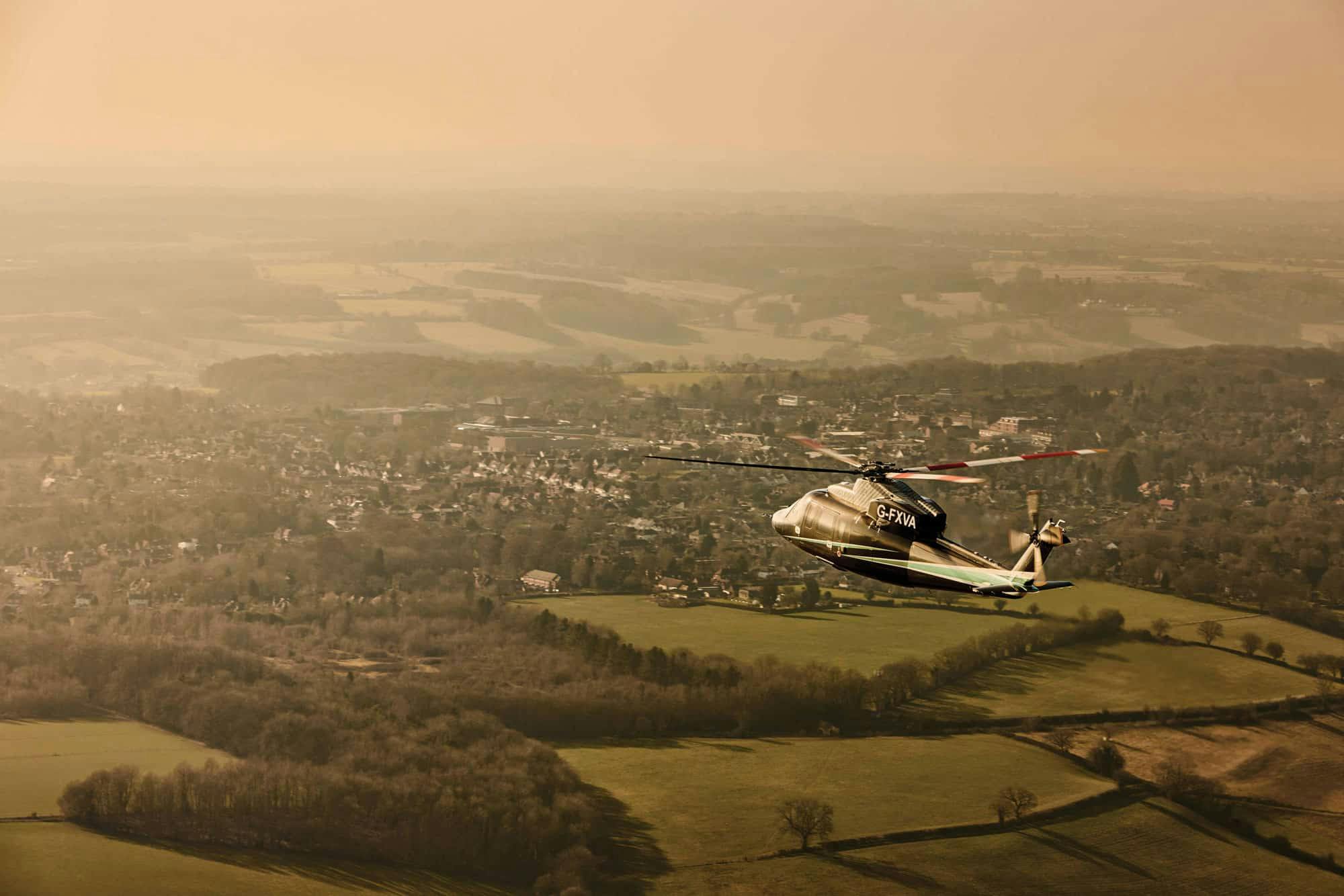 A flexjet helicopter flies over a suburban landscape with hazy skies