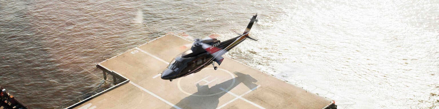 A flexjet helicopter lands on a heli pad just on a dock