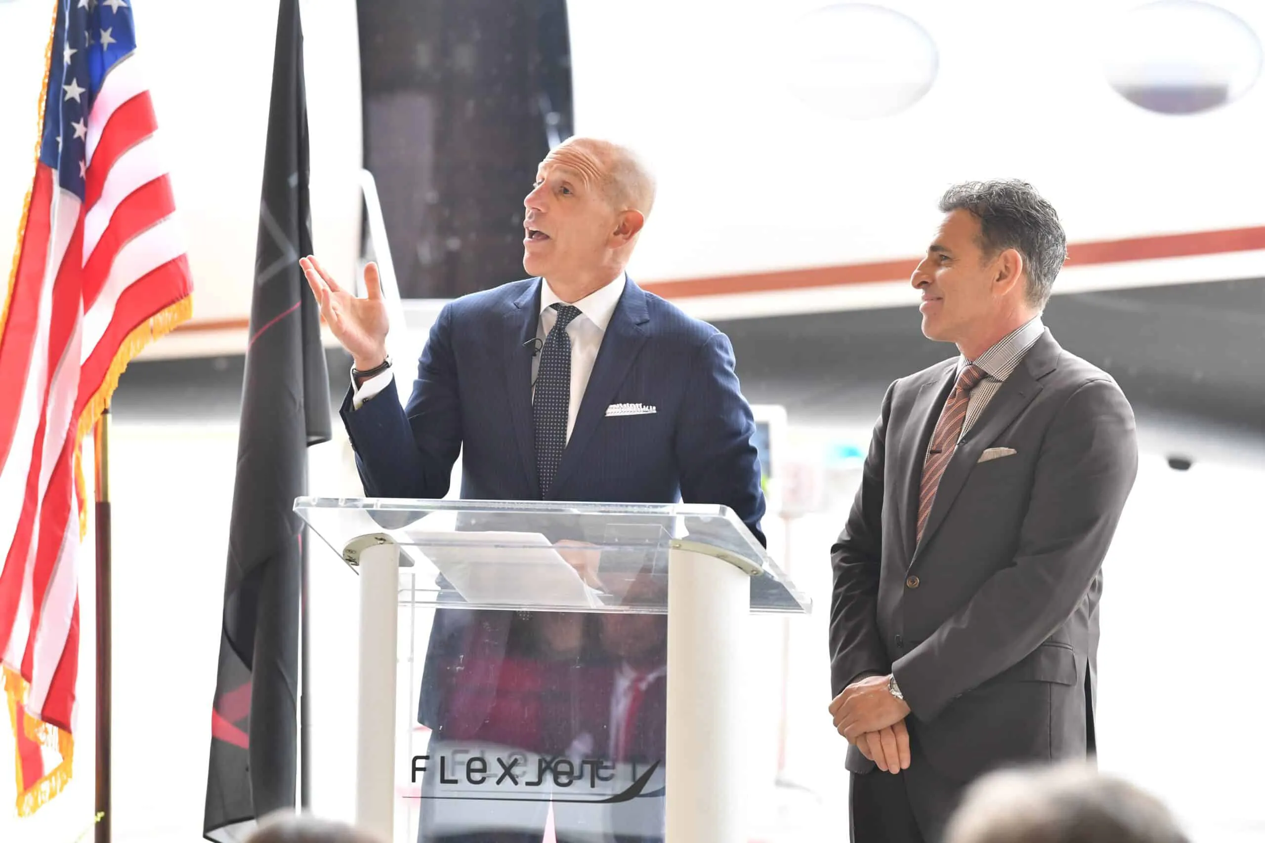 Mike and Kenn stand at a podium branded with the Flexjet logo