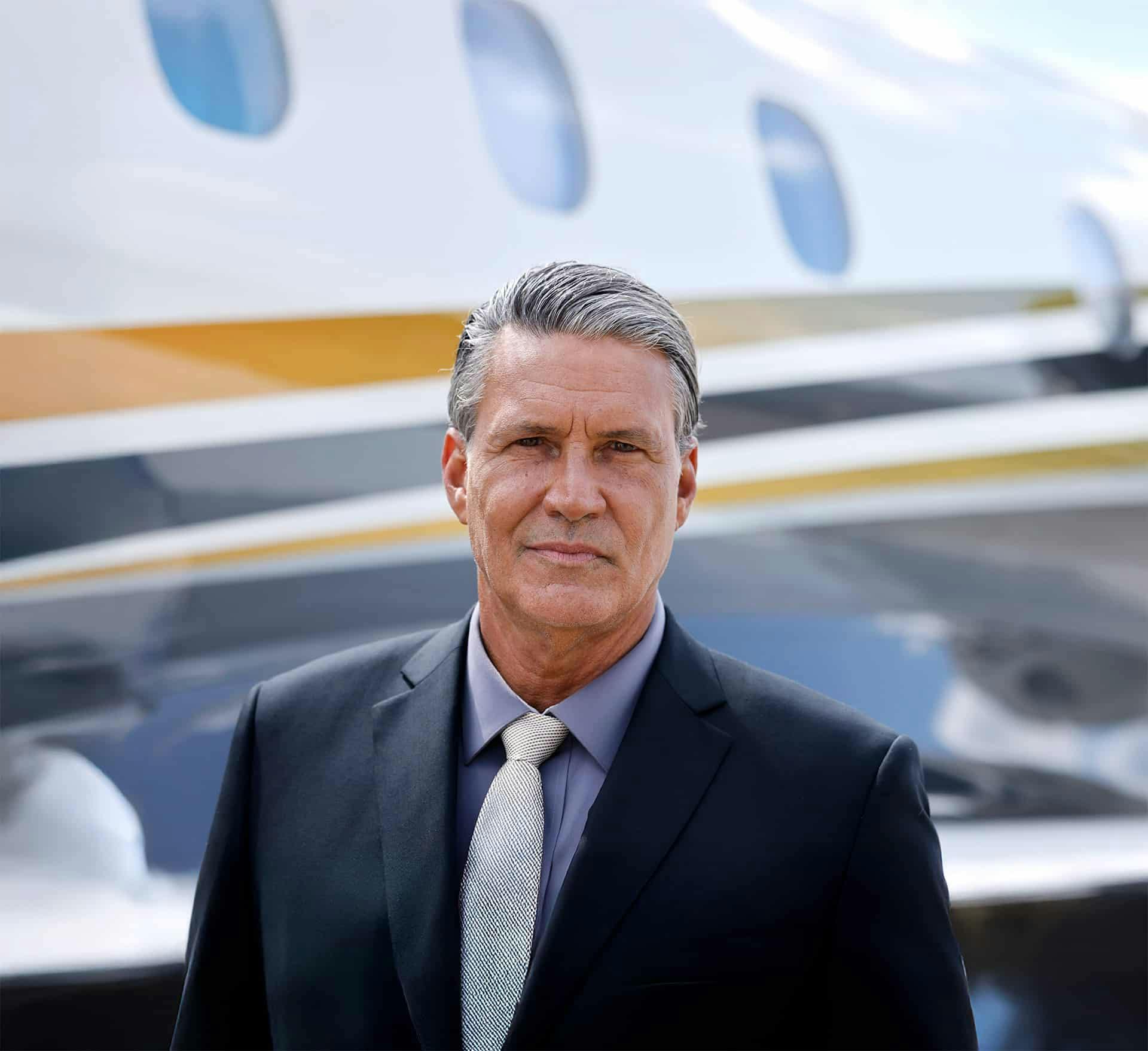 Male pilot poses in front of a flexjet aircraft with a stoic facial expression